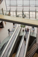 People on escalators in a modern building atrium.