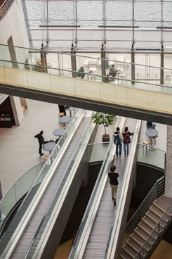 People on escalators in a modern building atrium.
