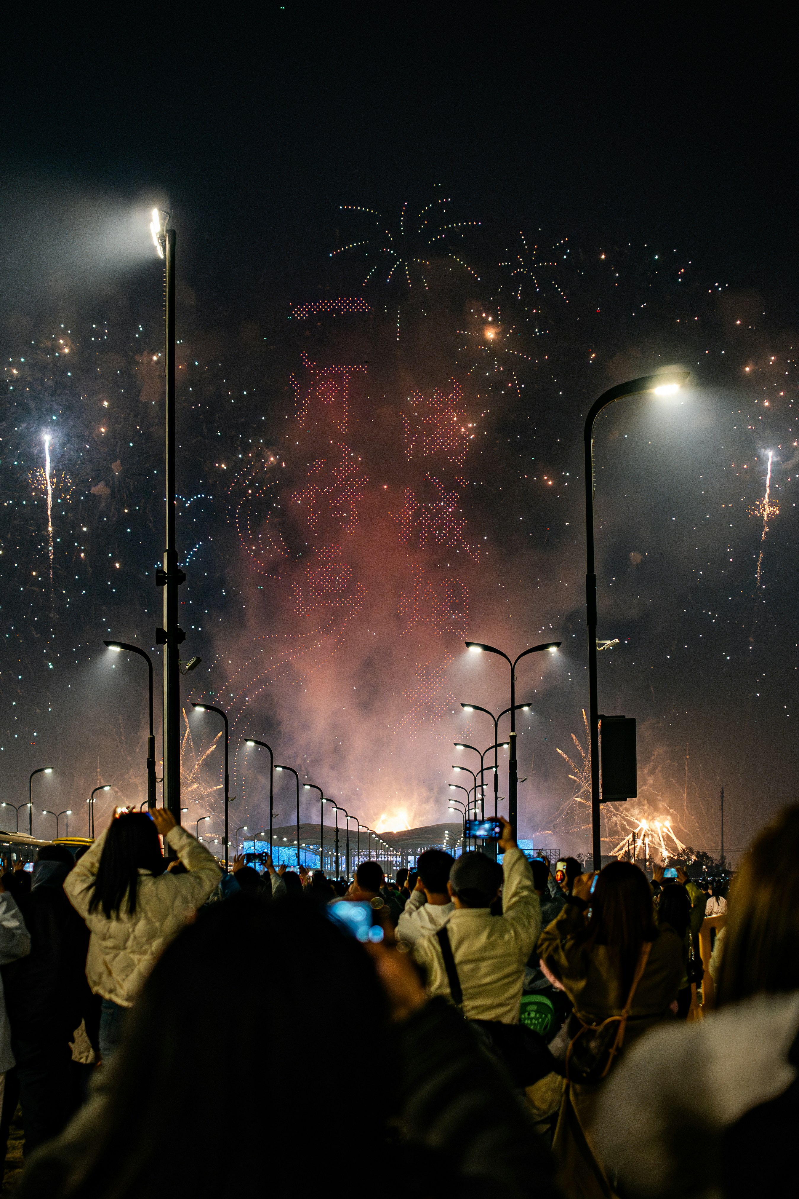 People watch fireworks display over bridge at night.