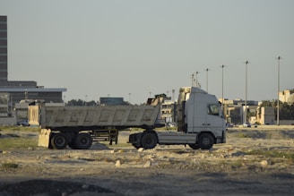 A white semi-truck with a dump trailer parked.