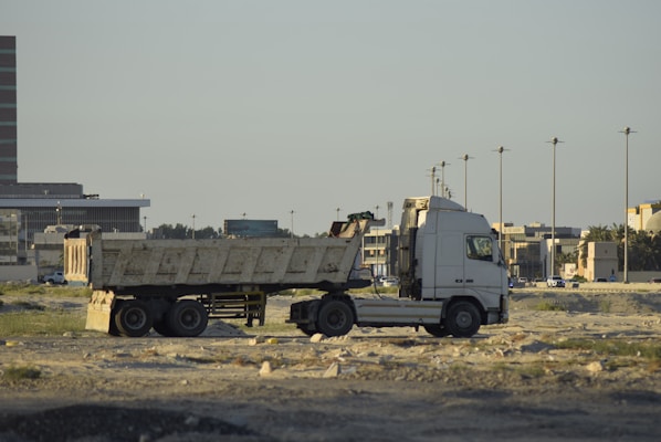 A white semi-truck with a dump trailer parked.