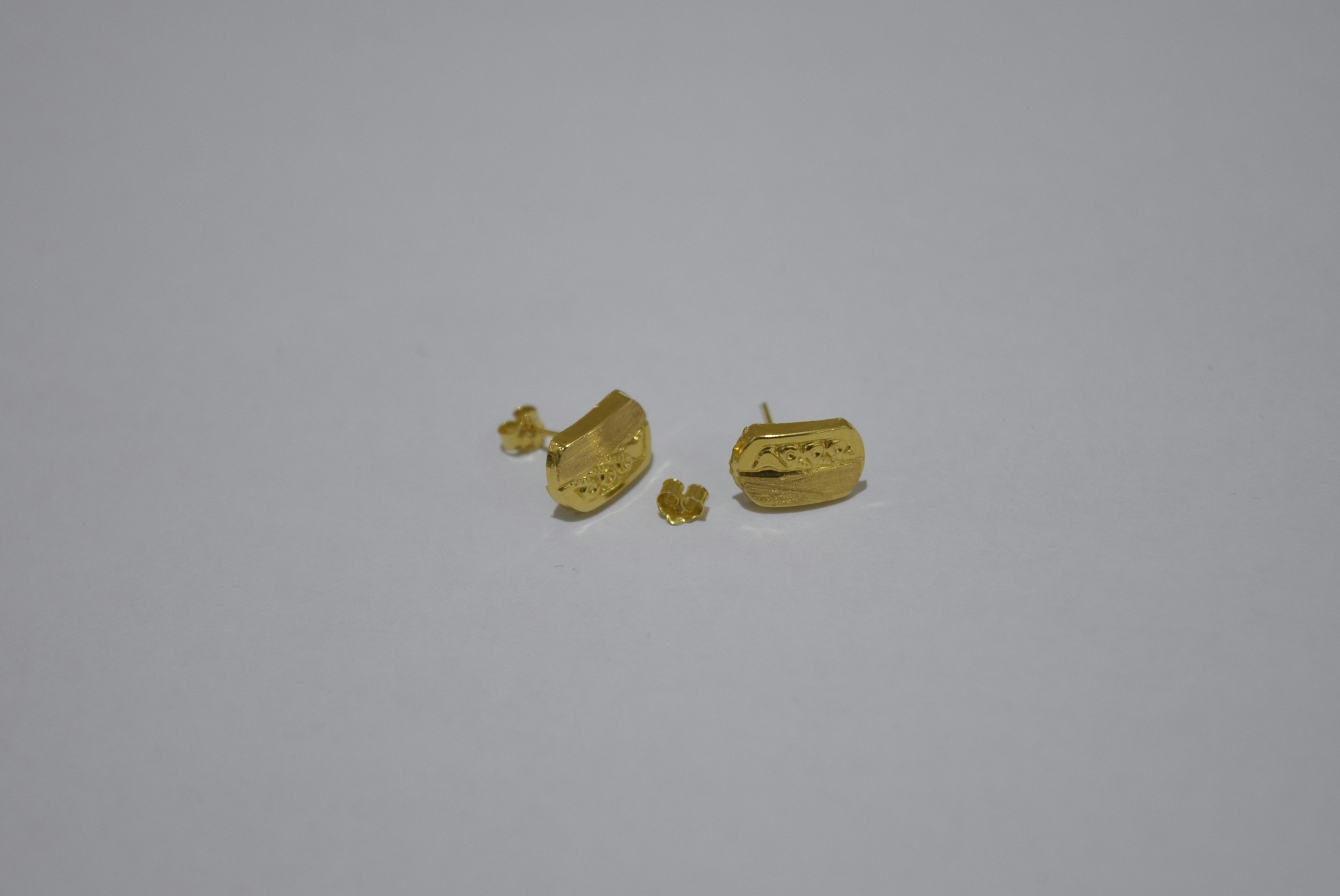 Two pairs of gold earrings on white background