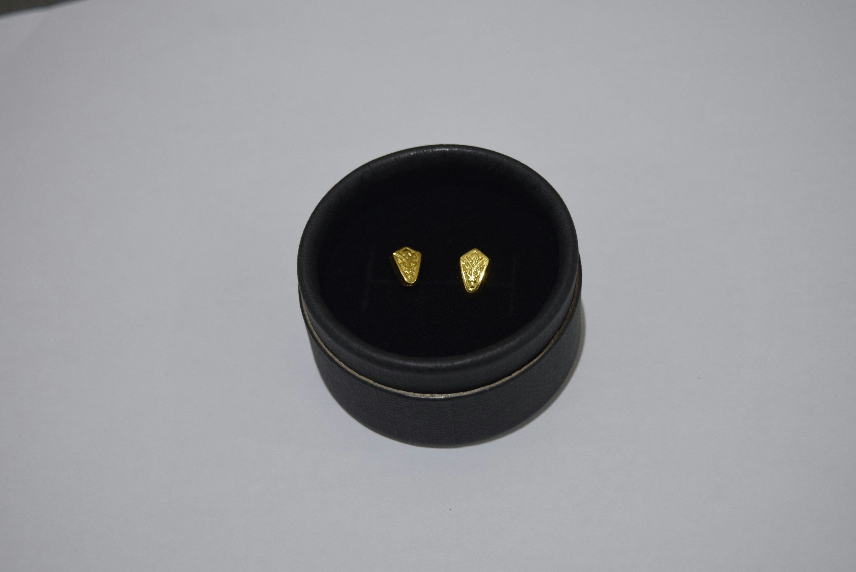 Gold stud earrings in a black jewelry box