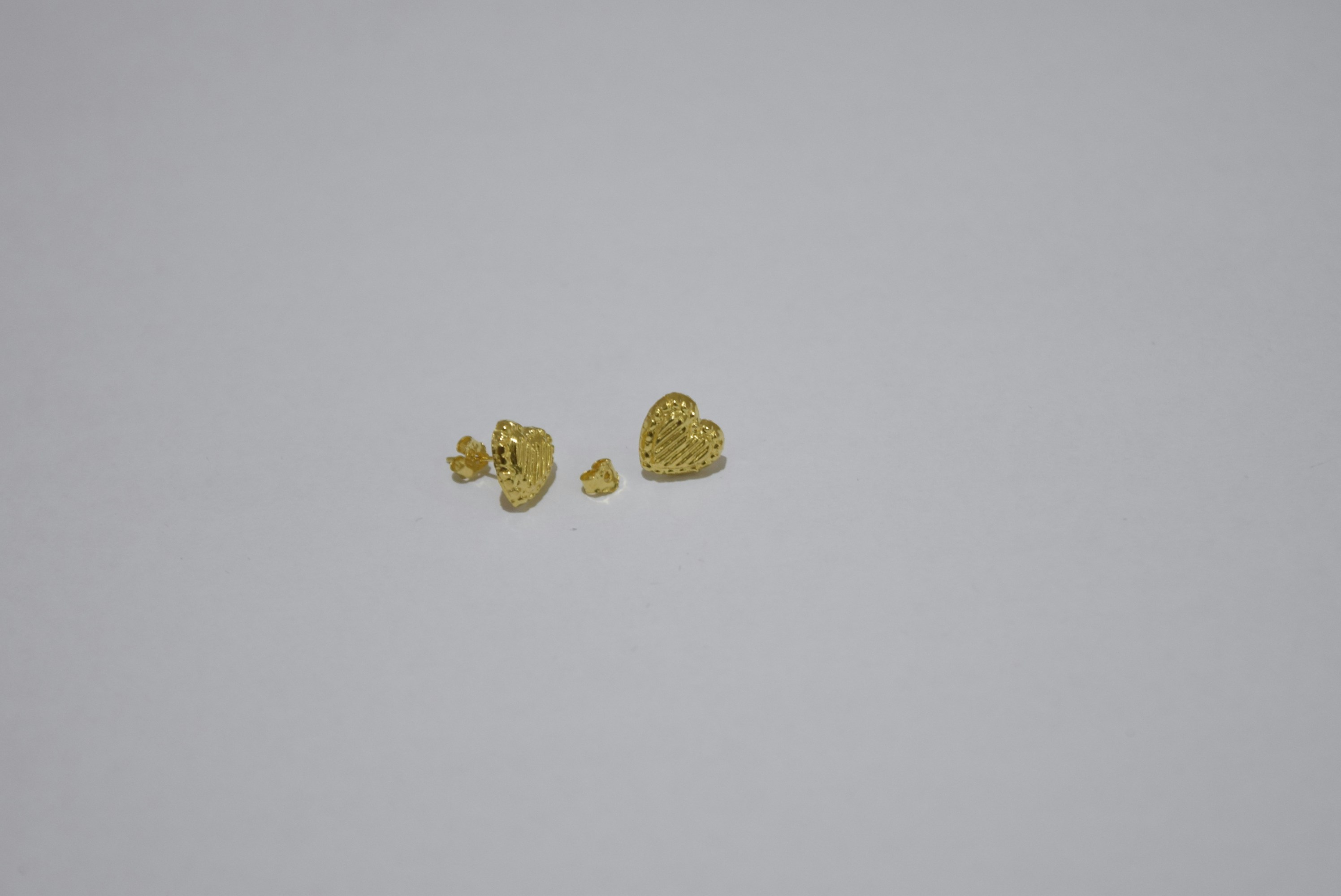 Gold heart-shaped earrings and small gold studs