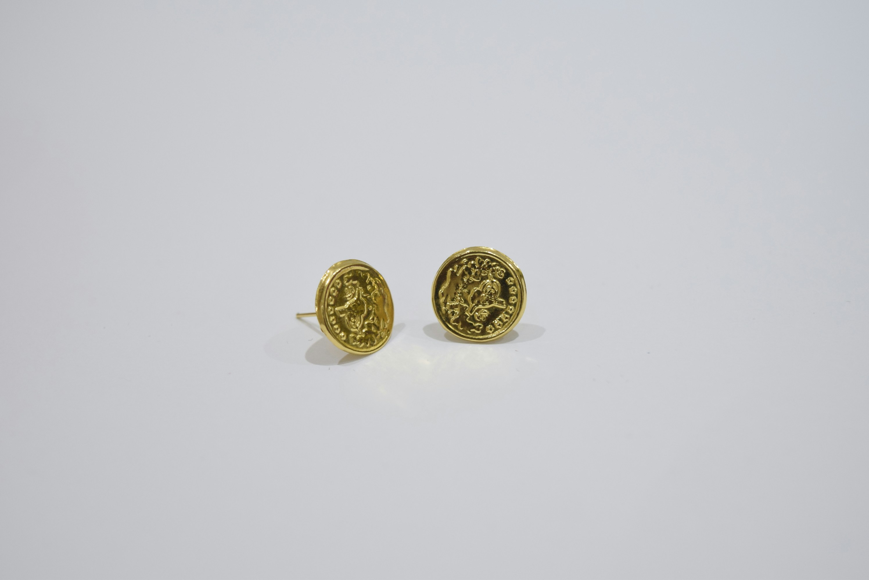 Two gold oval earrings with intricate designs