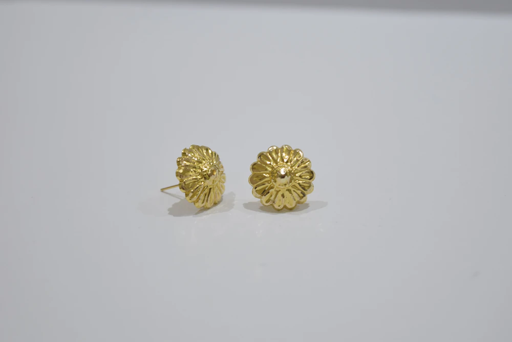 Gold flower-shaped stud earrings on a white background