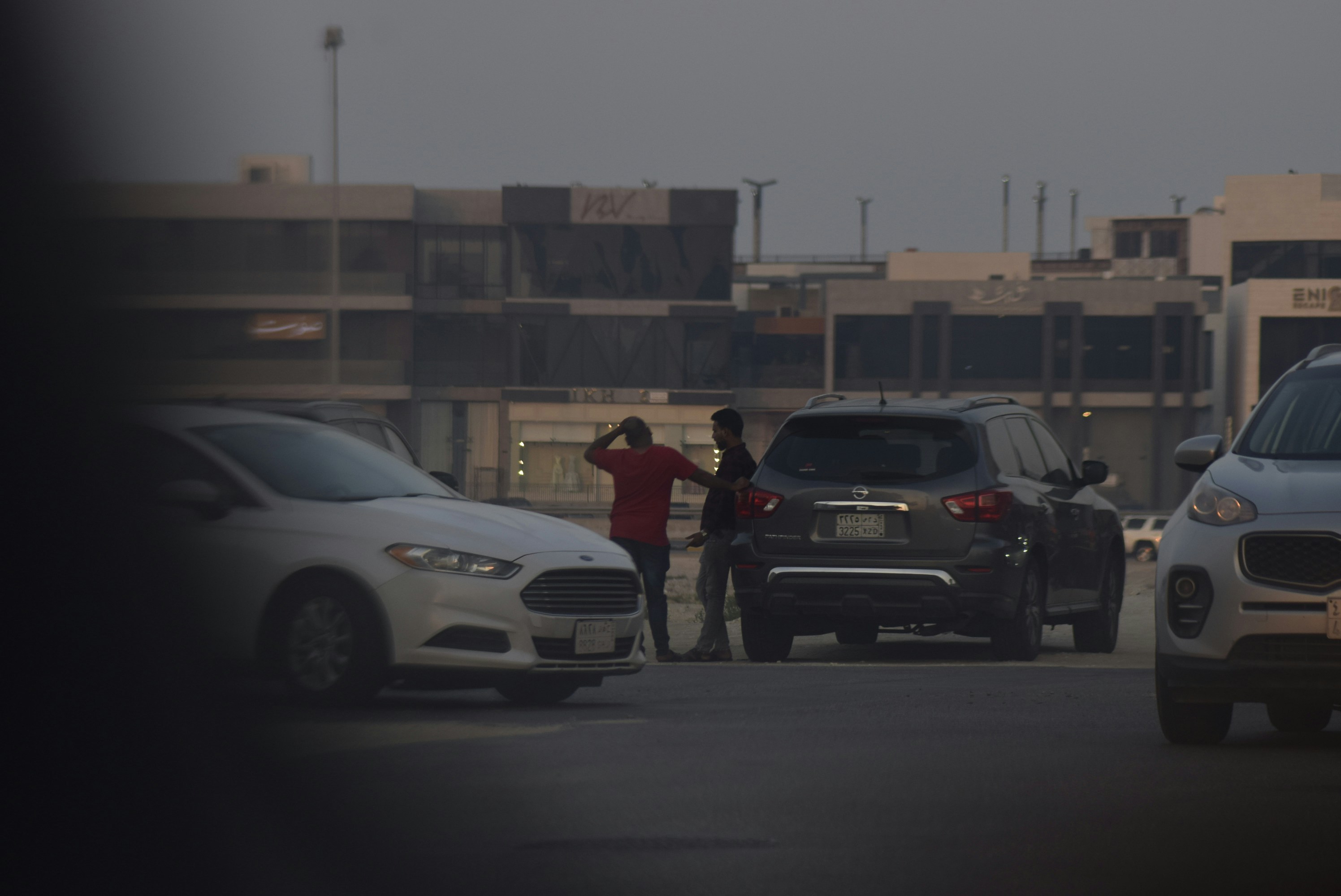 Two men standing between cars on a street