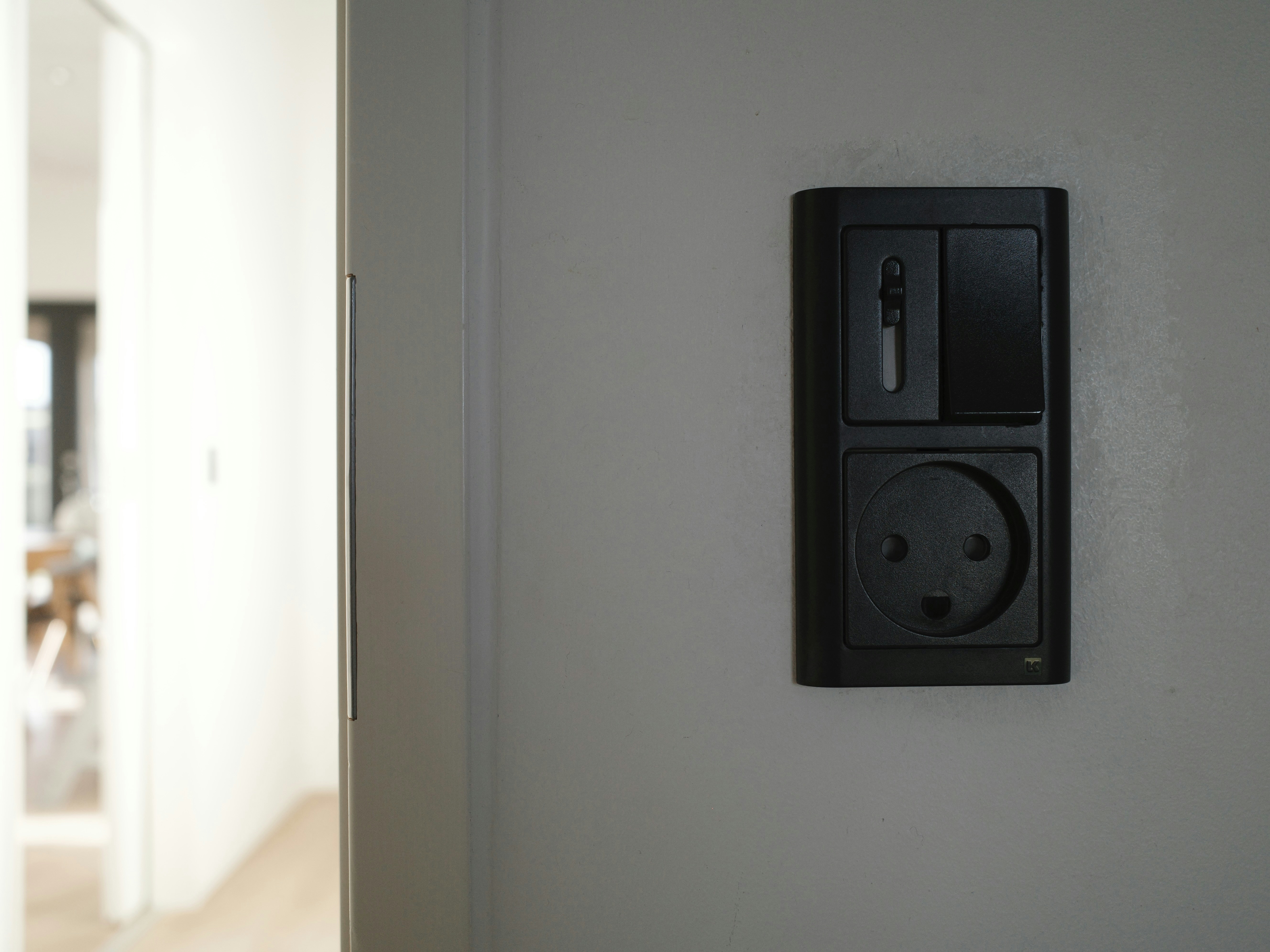 A black electrical outlet and switch on a wall.