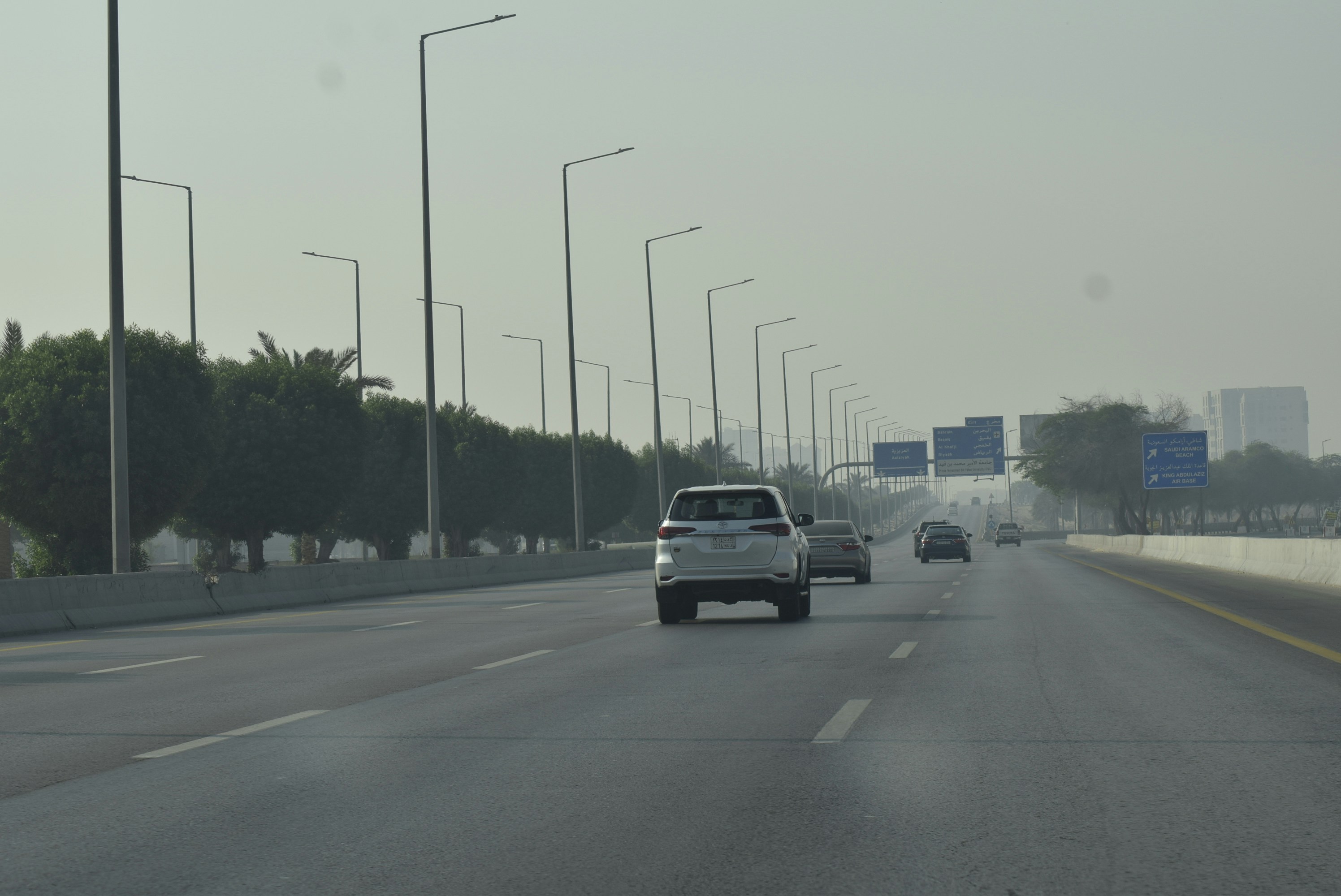 Cars driving on a highway with streetlights.