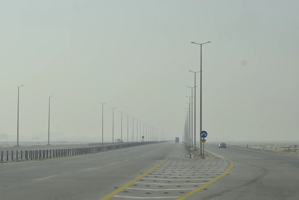 Long, straight highway with multiple lanes and white lines guides vehicles along its path