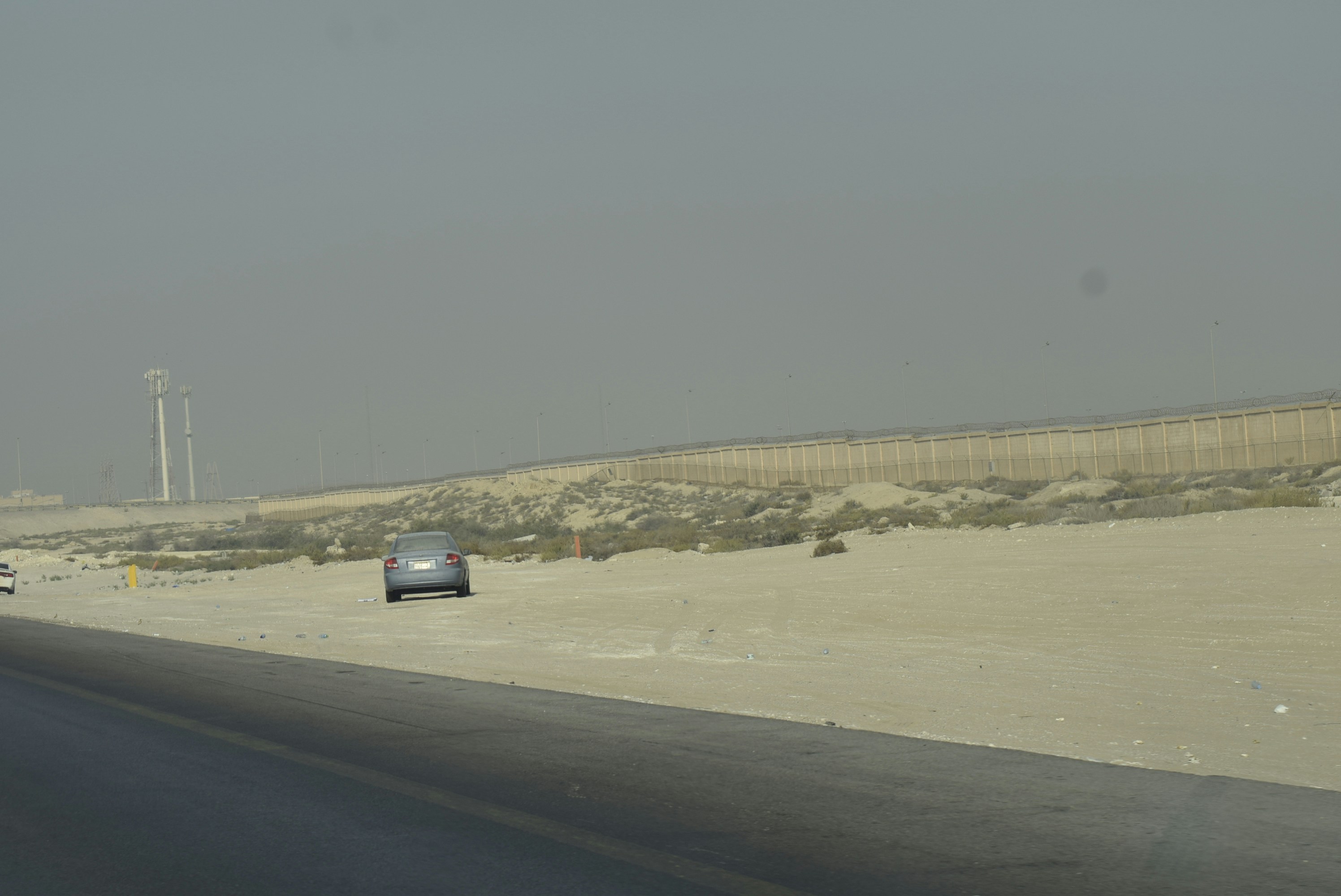Cars driving on a desert highway with a barrier.