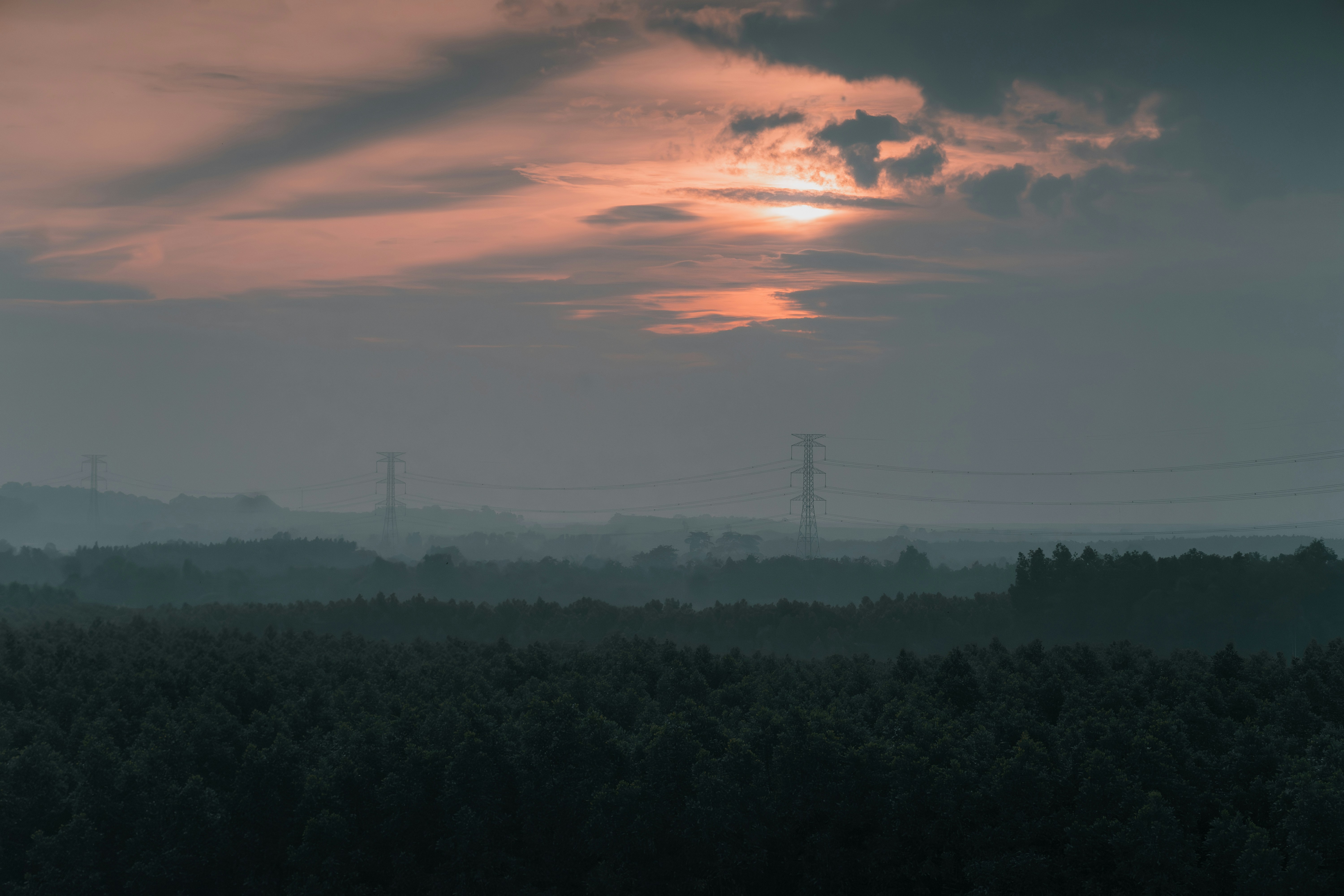 Misty sunrise over a dark forest landscape
