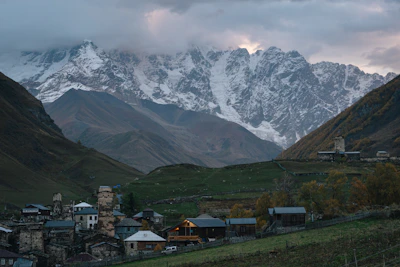 Village nestled in a valley with snowy mountains.