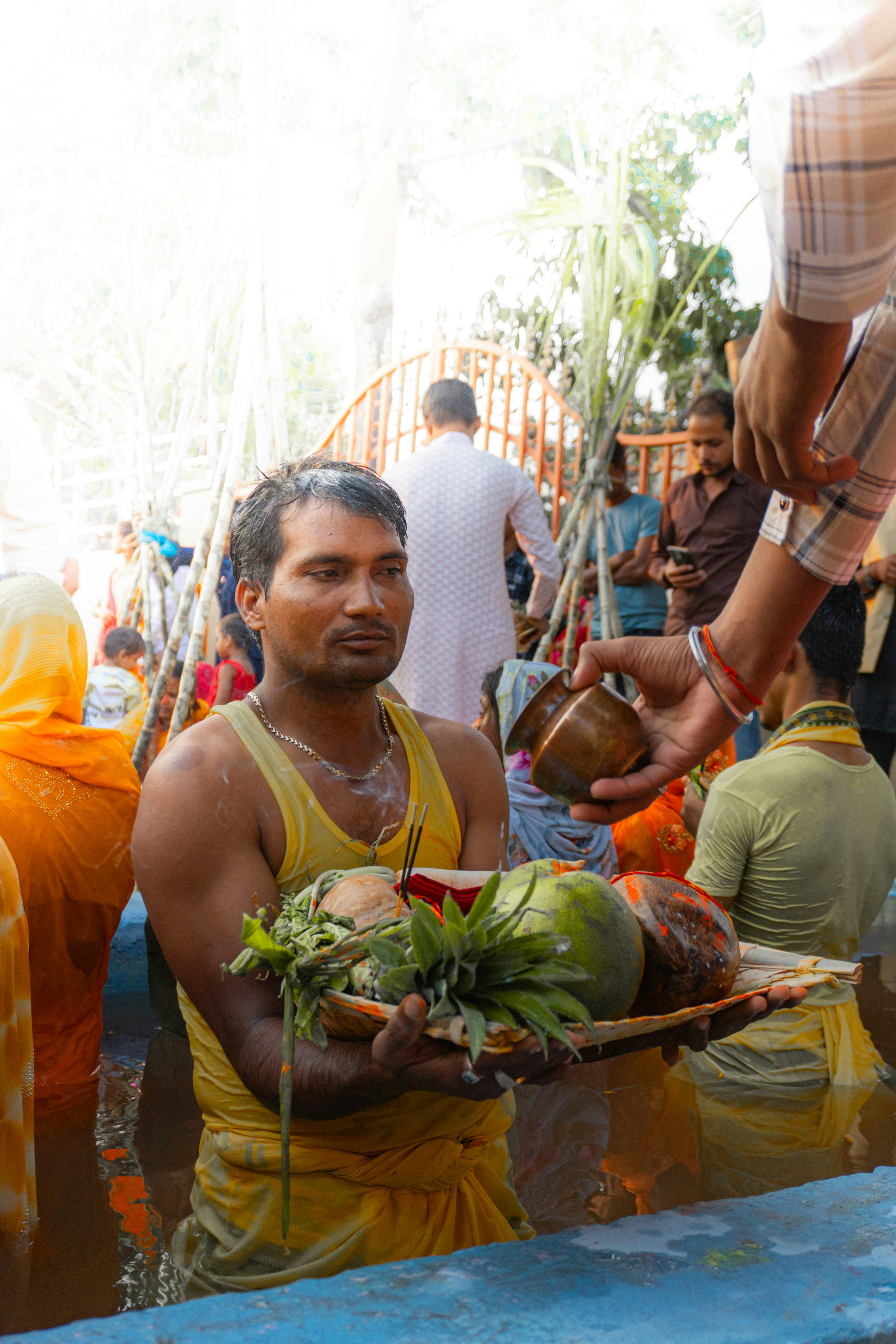 Man in water holding tray with fruits, receiving offering.