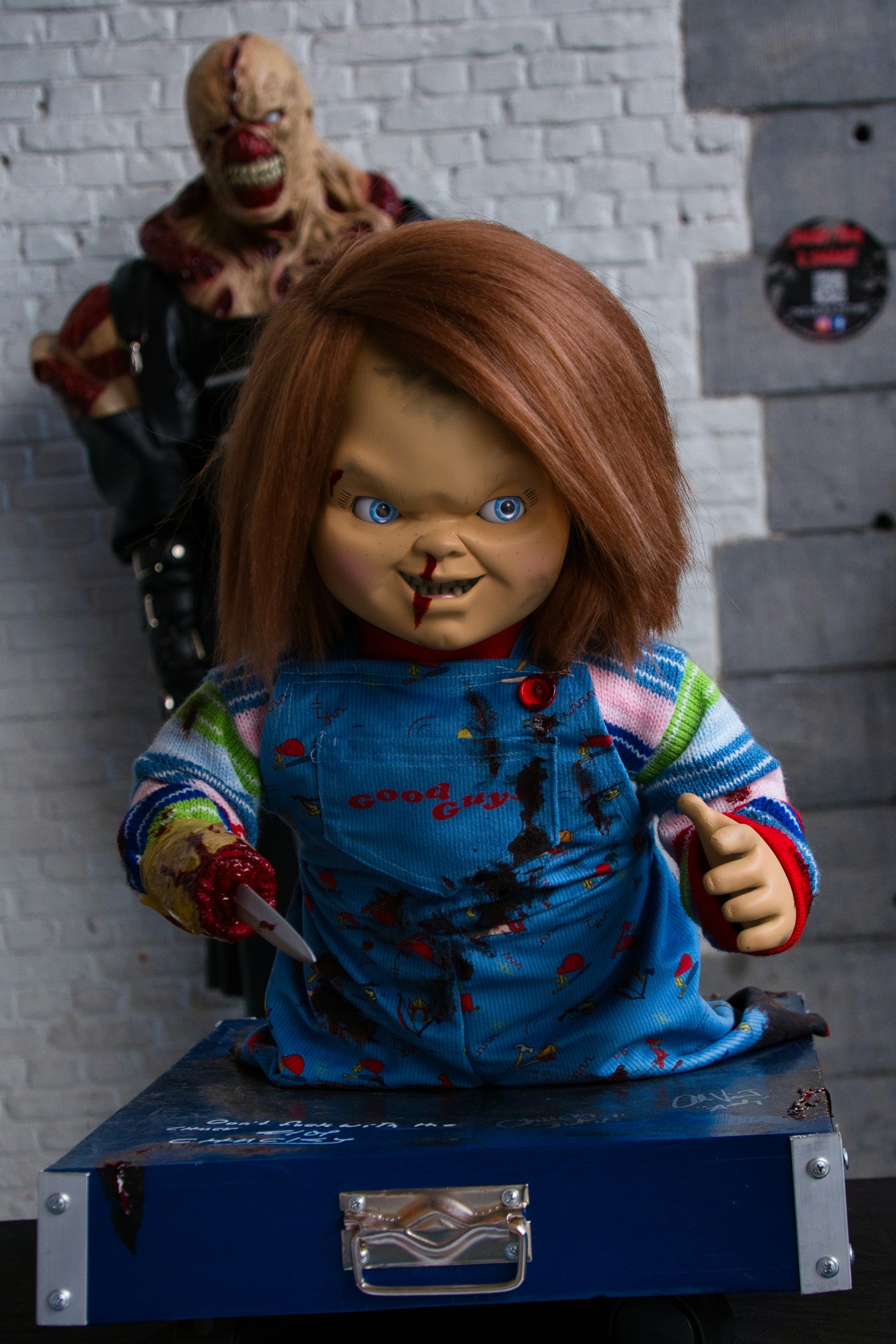 Chucky doll with knife and nemesis figure behind.