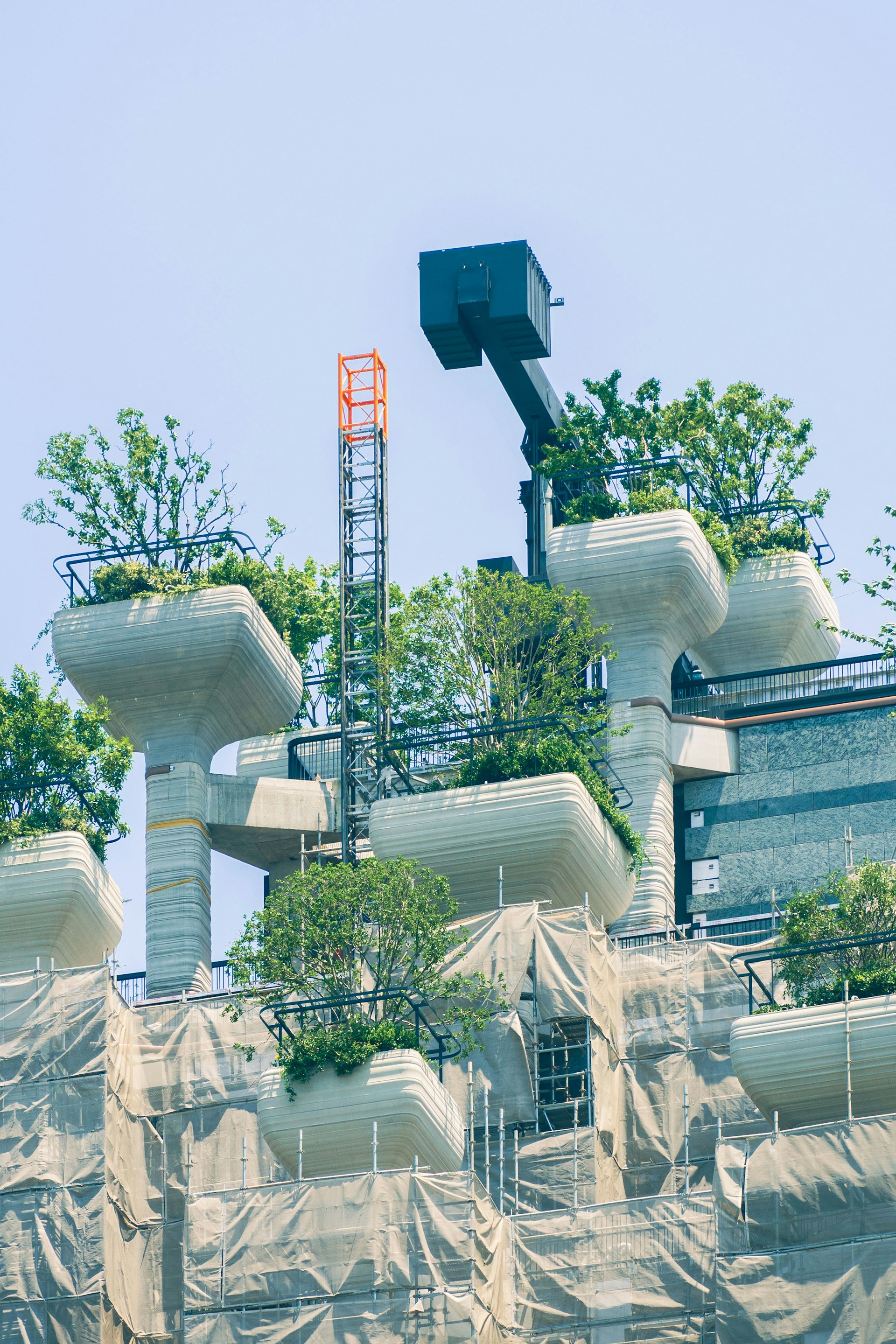 Modern building with green rooftop gardens and scaffolding.