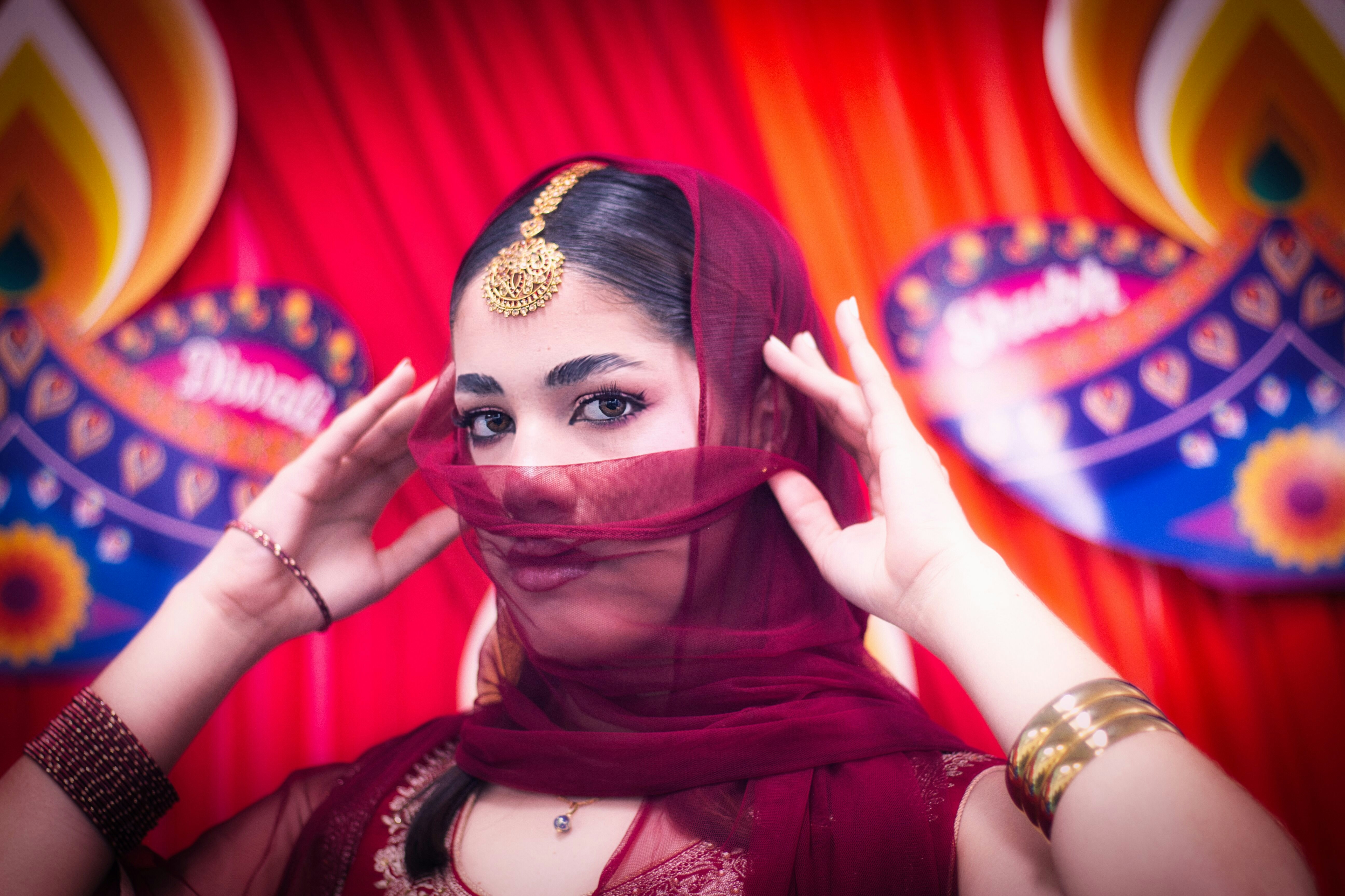 A close-up portrait of a woman wearing traditional South Asian jewelry and attire