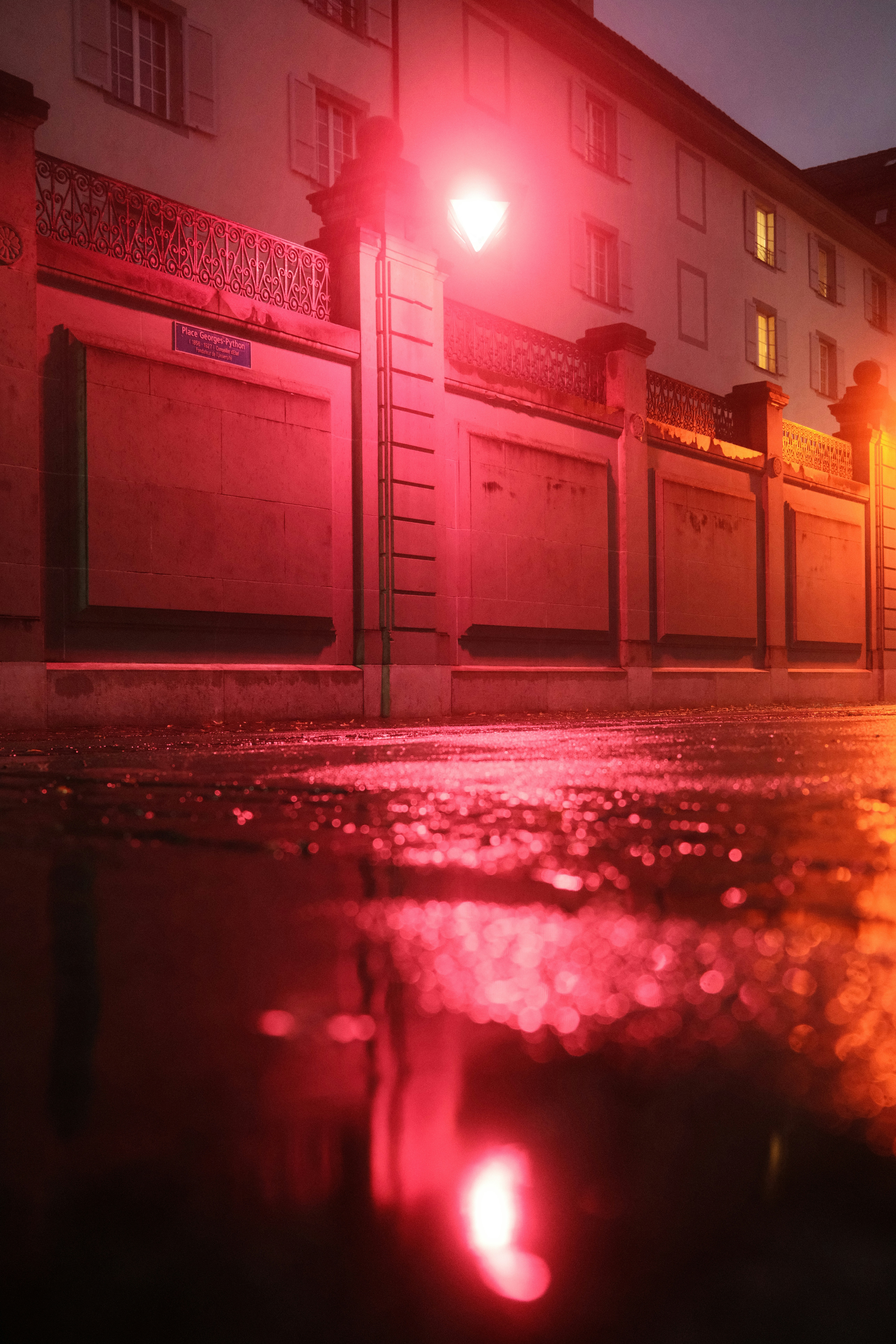 Red traffic light reflects on wet street at night