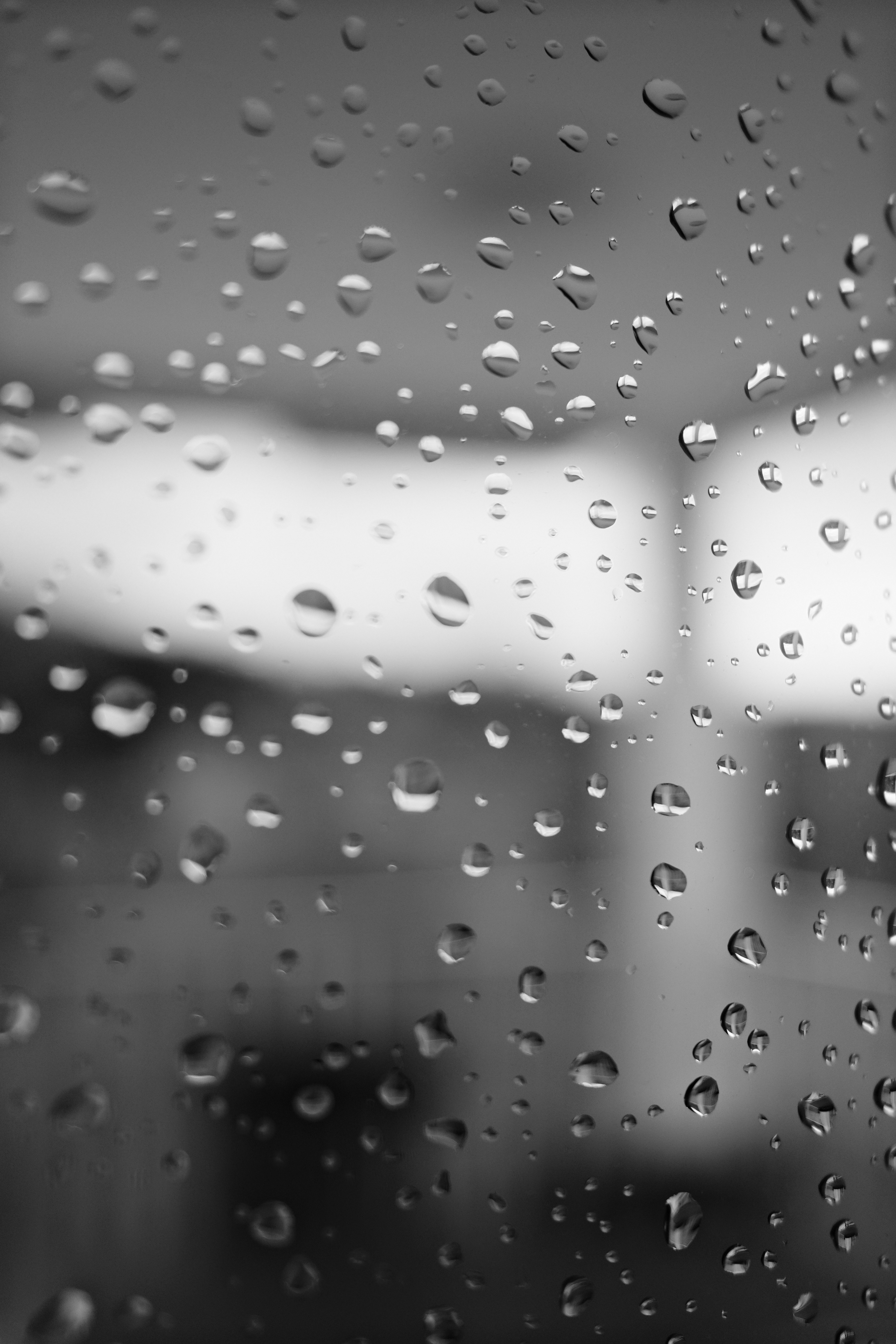 Raindrops on a window pane with blurred background.