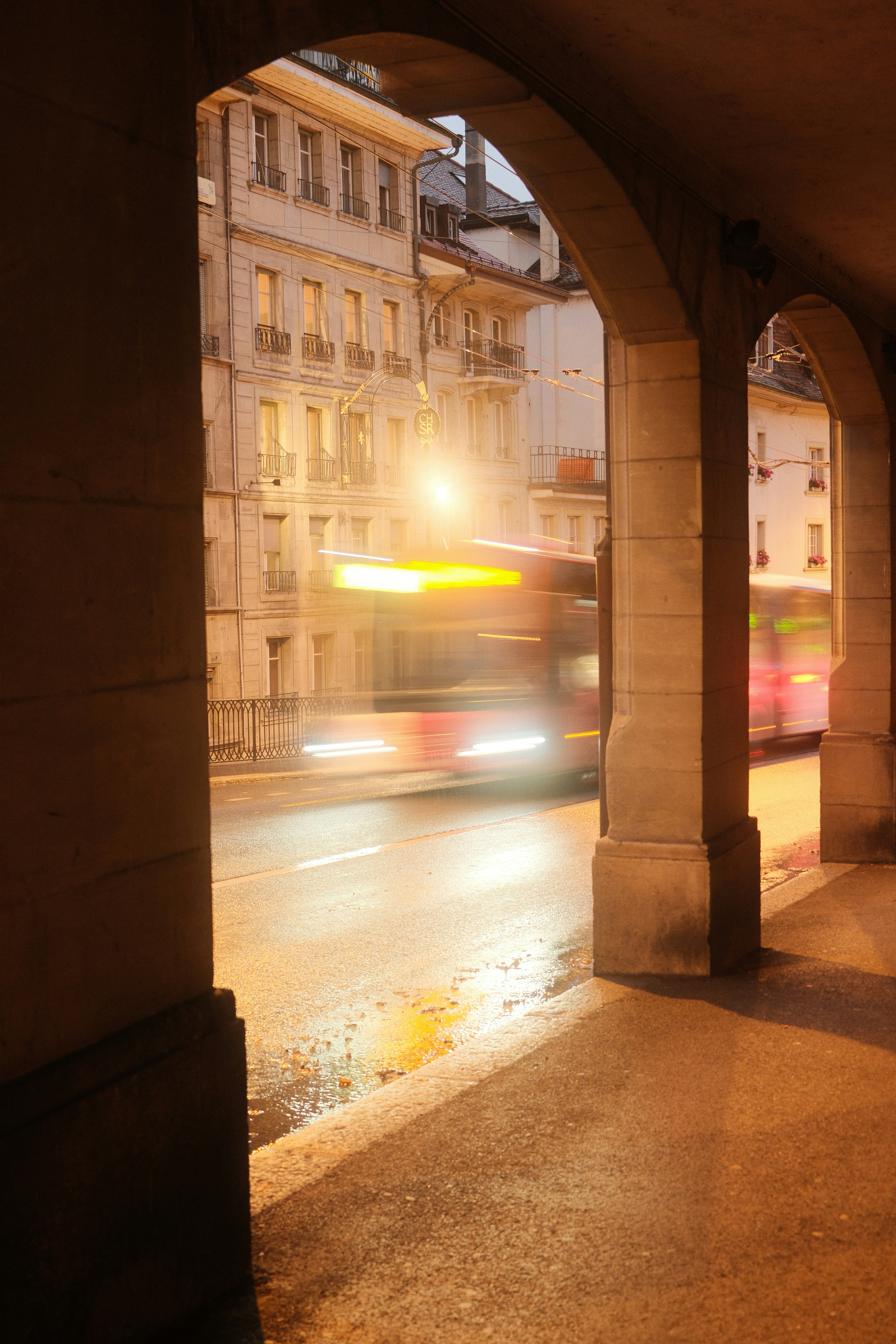 Bus driving past old buildings at night