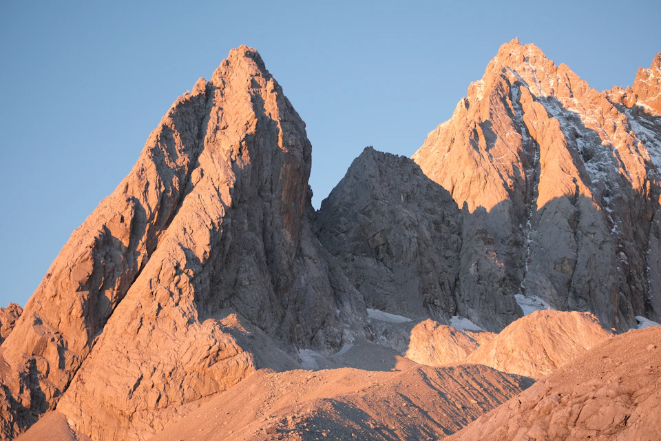 Mountain range with three peaks, each exhibiting unique characteristics and varying landscape features