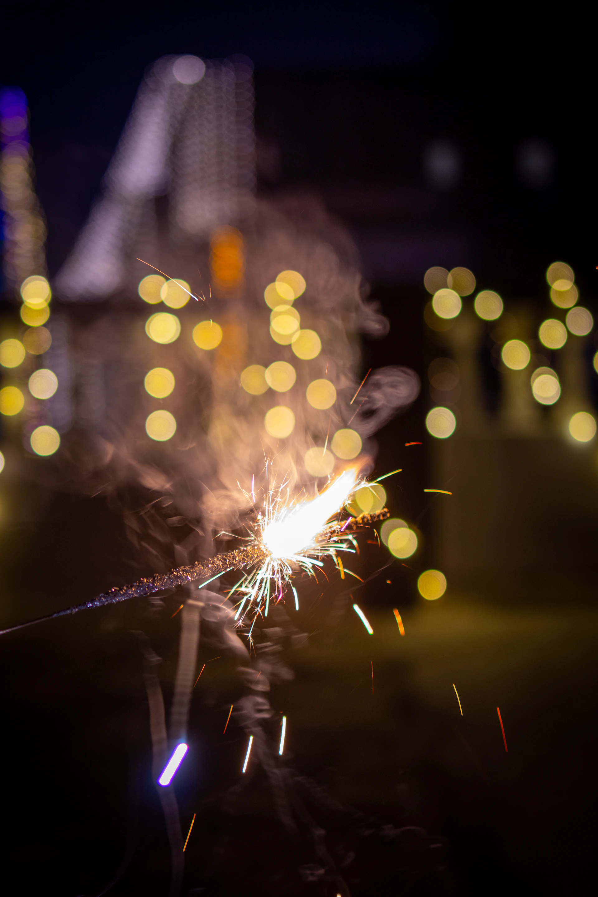 Sparkler burning brightly with bokeh lights in background