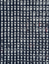 Rows of white cars parked neatly from above
