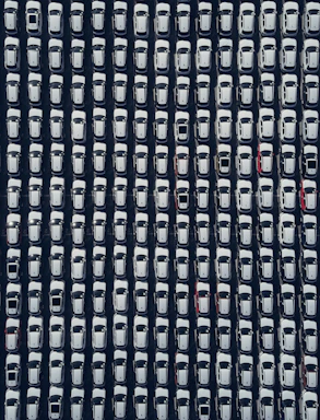 Rows of white cars parked neatly from above