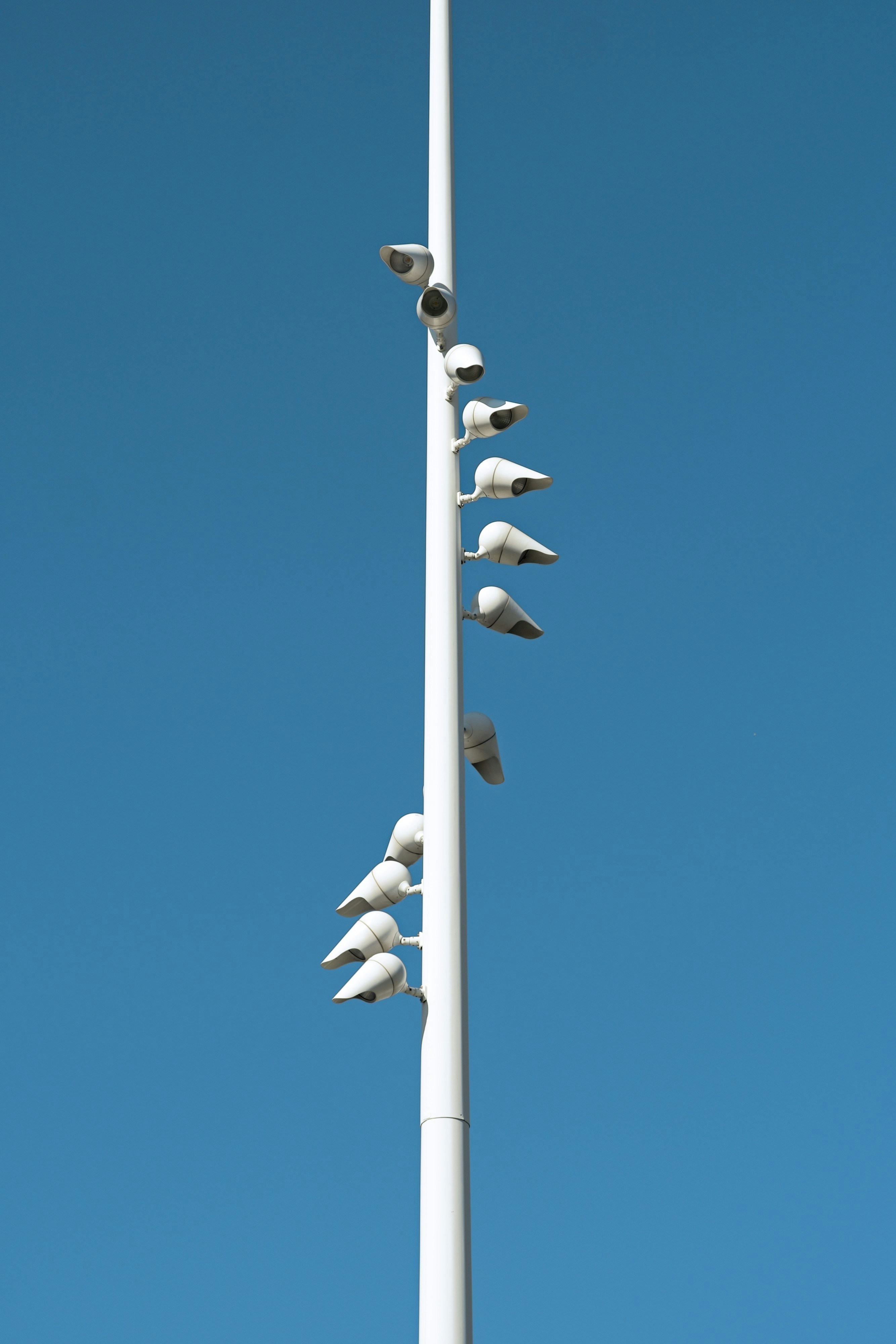 White pole with security cameras against blue sky