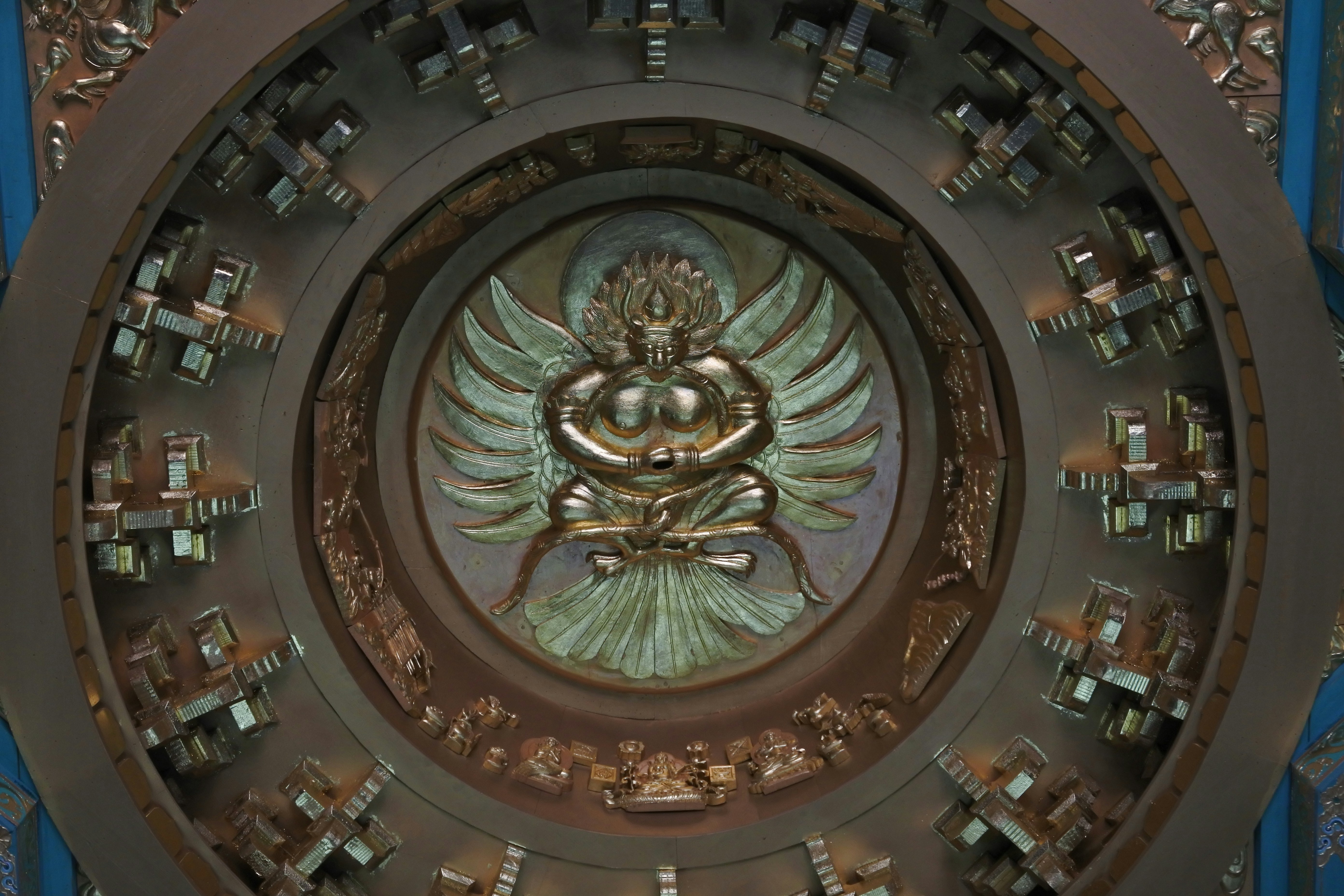 Ornate golden deity with wings in circular frame.