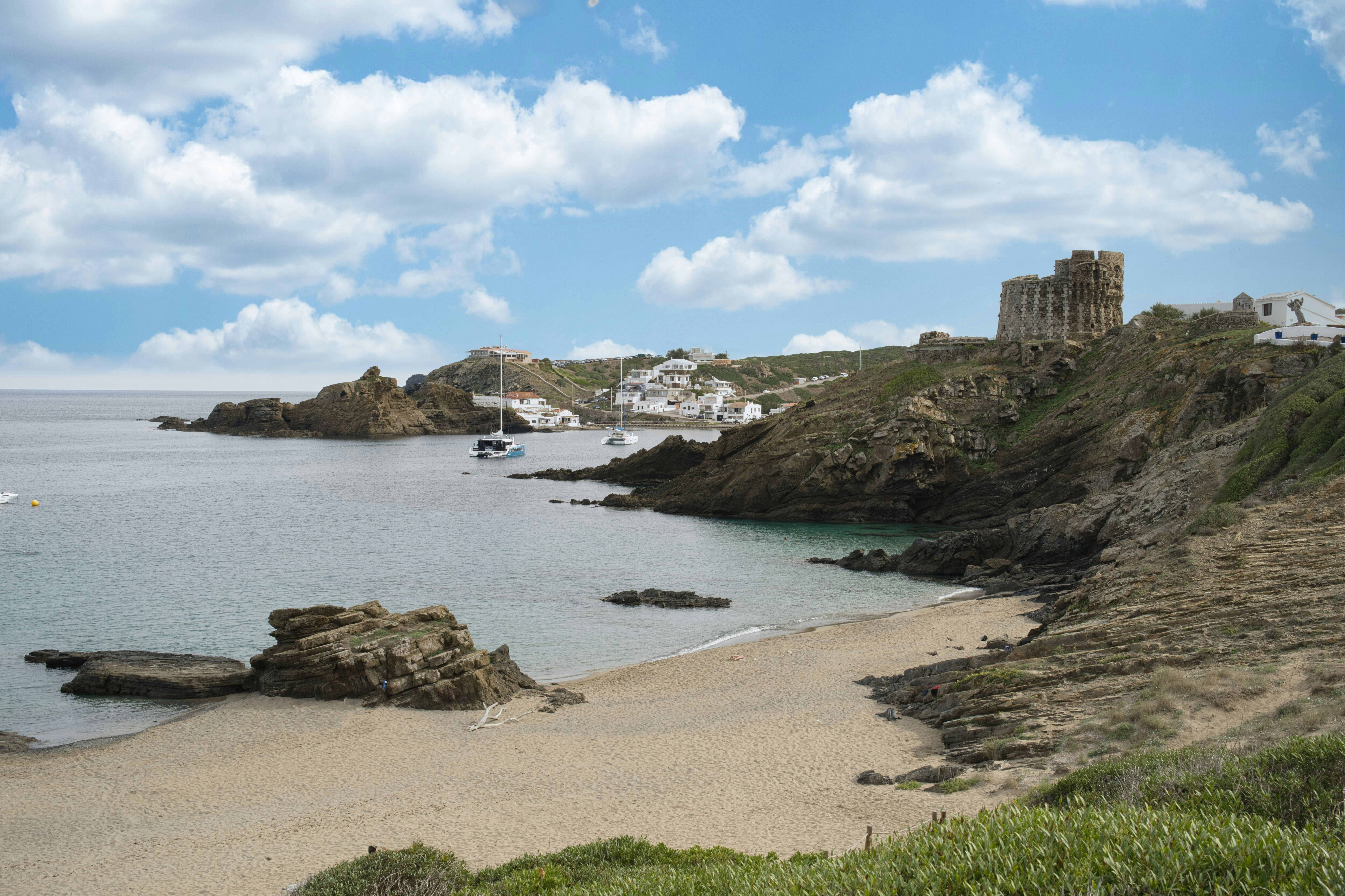 Coastal village with a sandy beach and rocky cliffs.