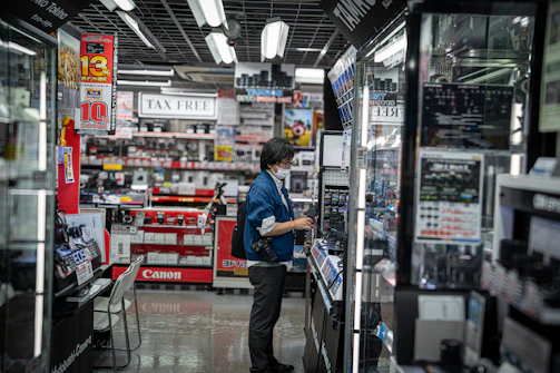 Person browsing electronics in a brightly lit store.