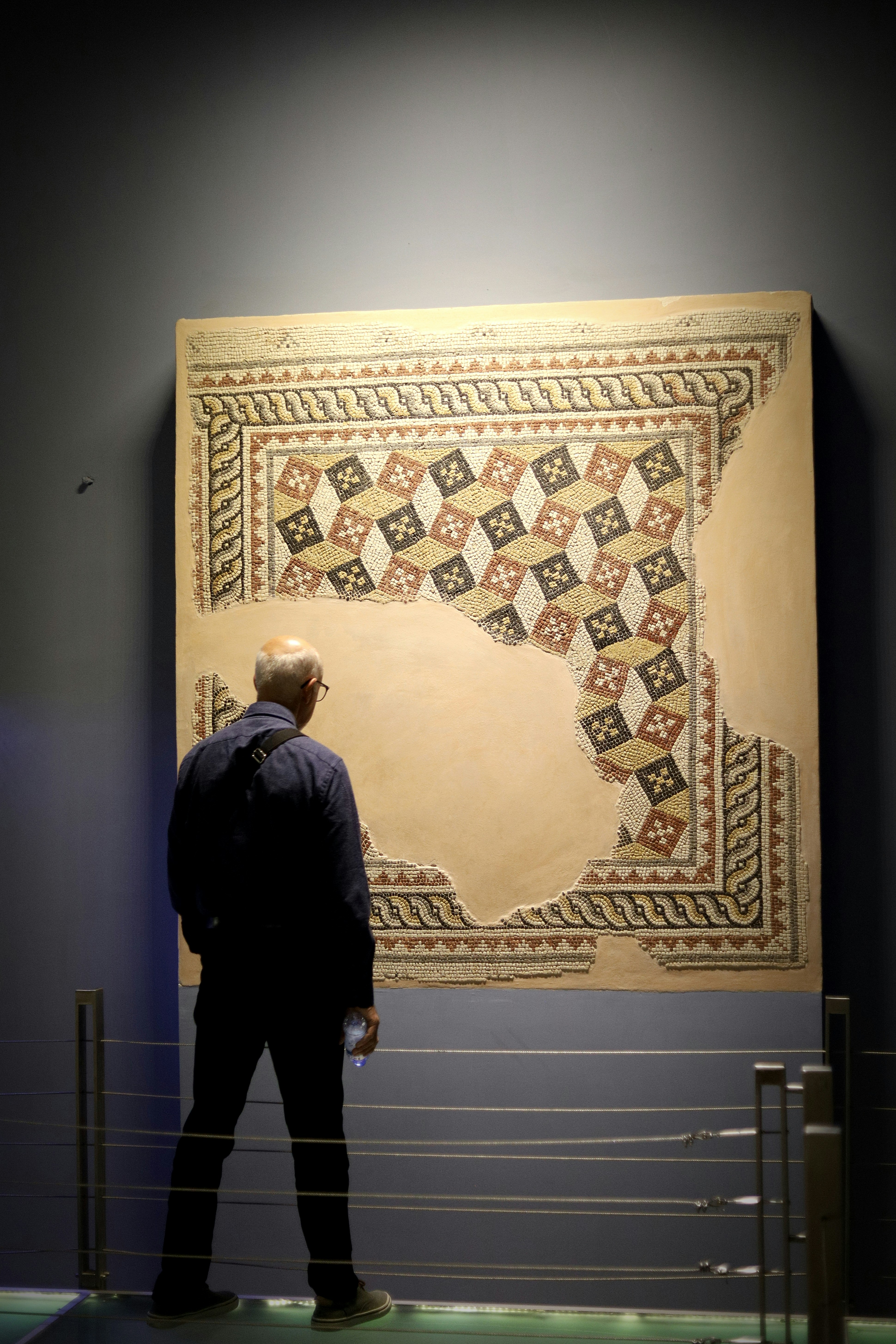 Mann betrachtet antike Mosaikkunstwerke in einem Museum