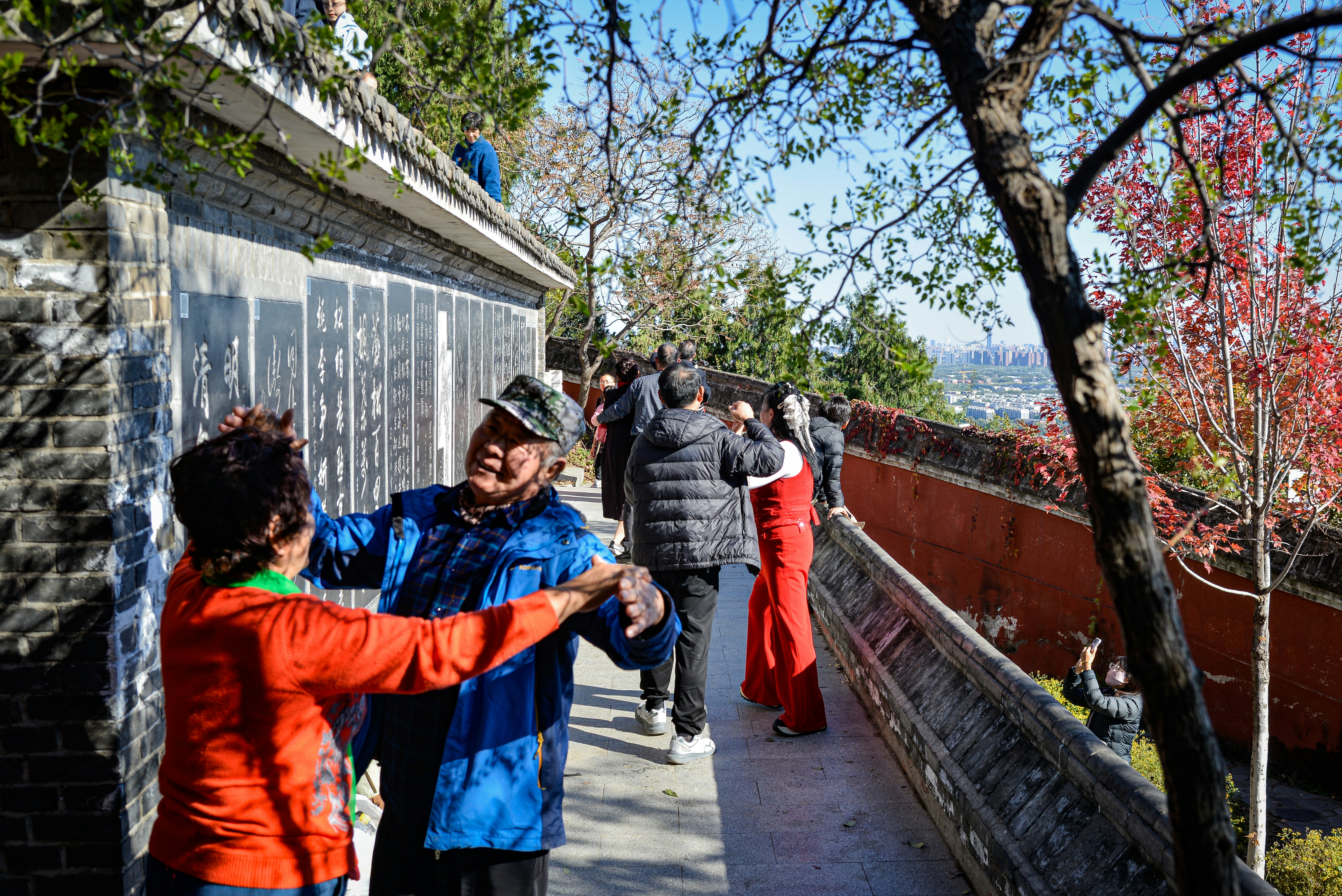 People walking on a path beside a wall
