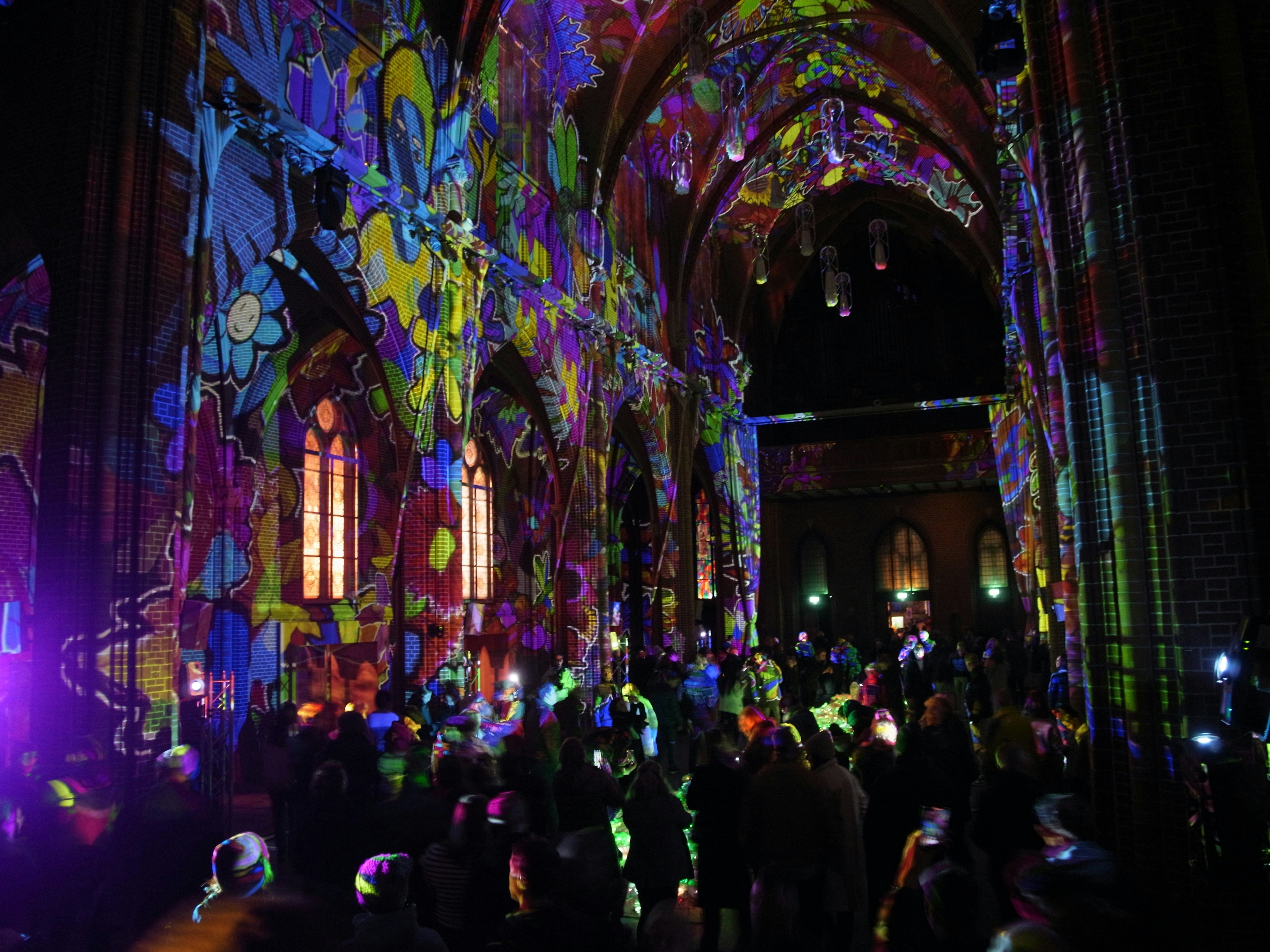 Colorful light projections illuminate a gothic cathedral interior.