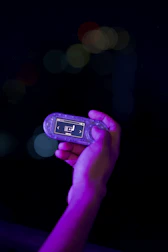 Hand holding illuminated portable music player at night