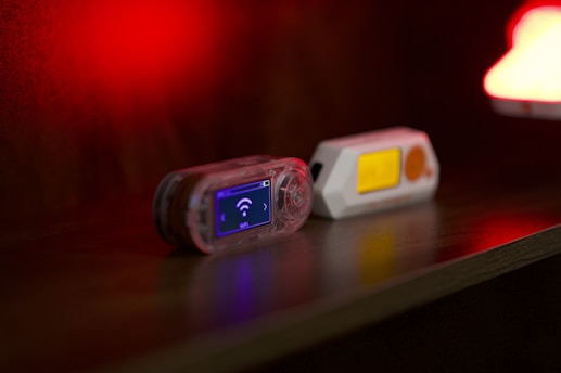 Two small electronic devices on a dark surface.