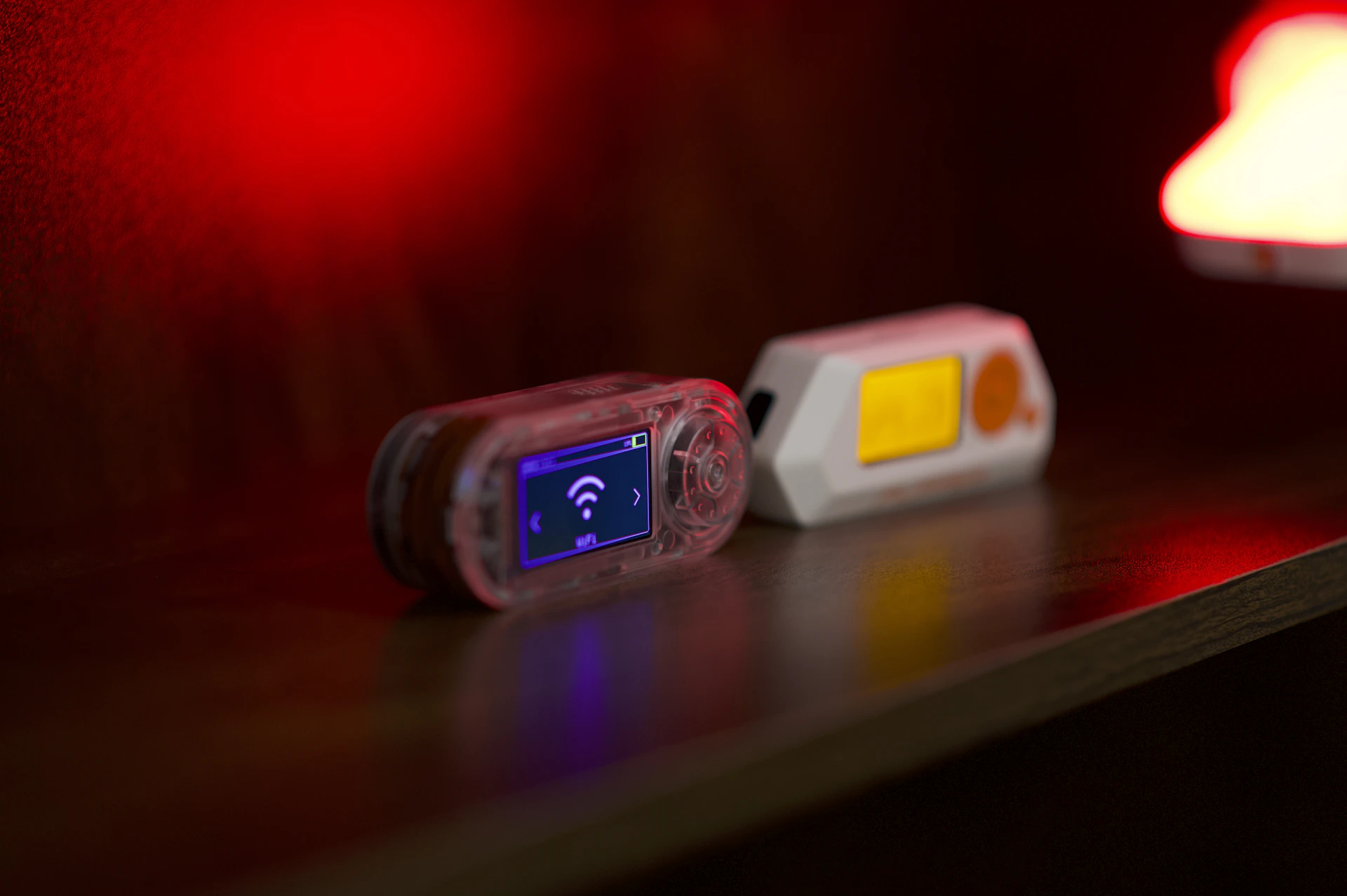 Two small electronic devices on a dark surface.