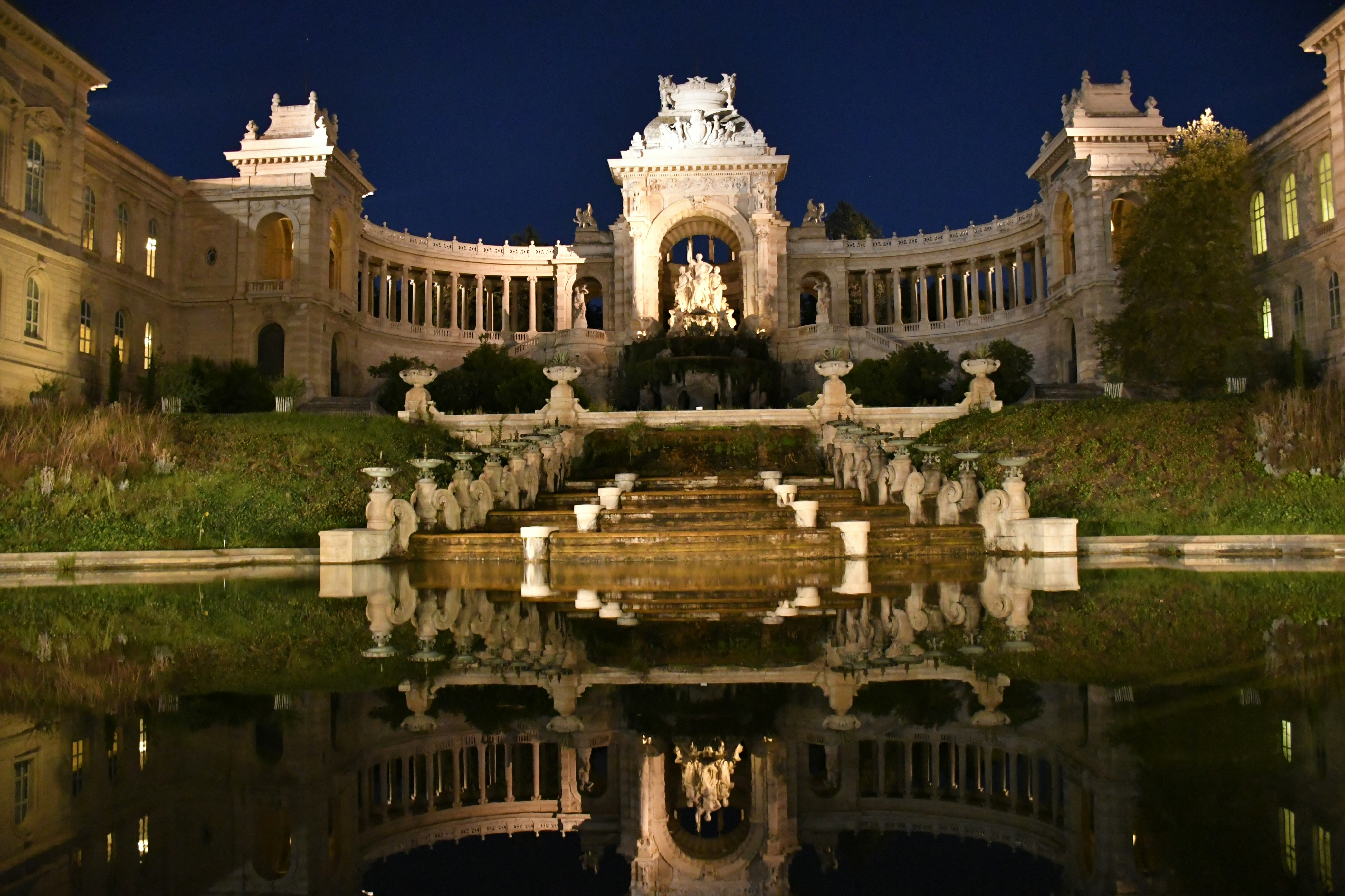 Ornate building with fountain and reflection at night