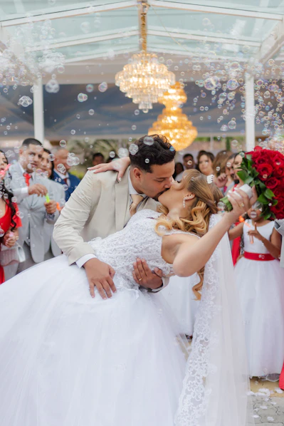 Bride and groom kiss amidst bubbles at wedding ceremony.