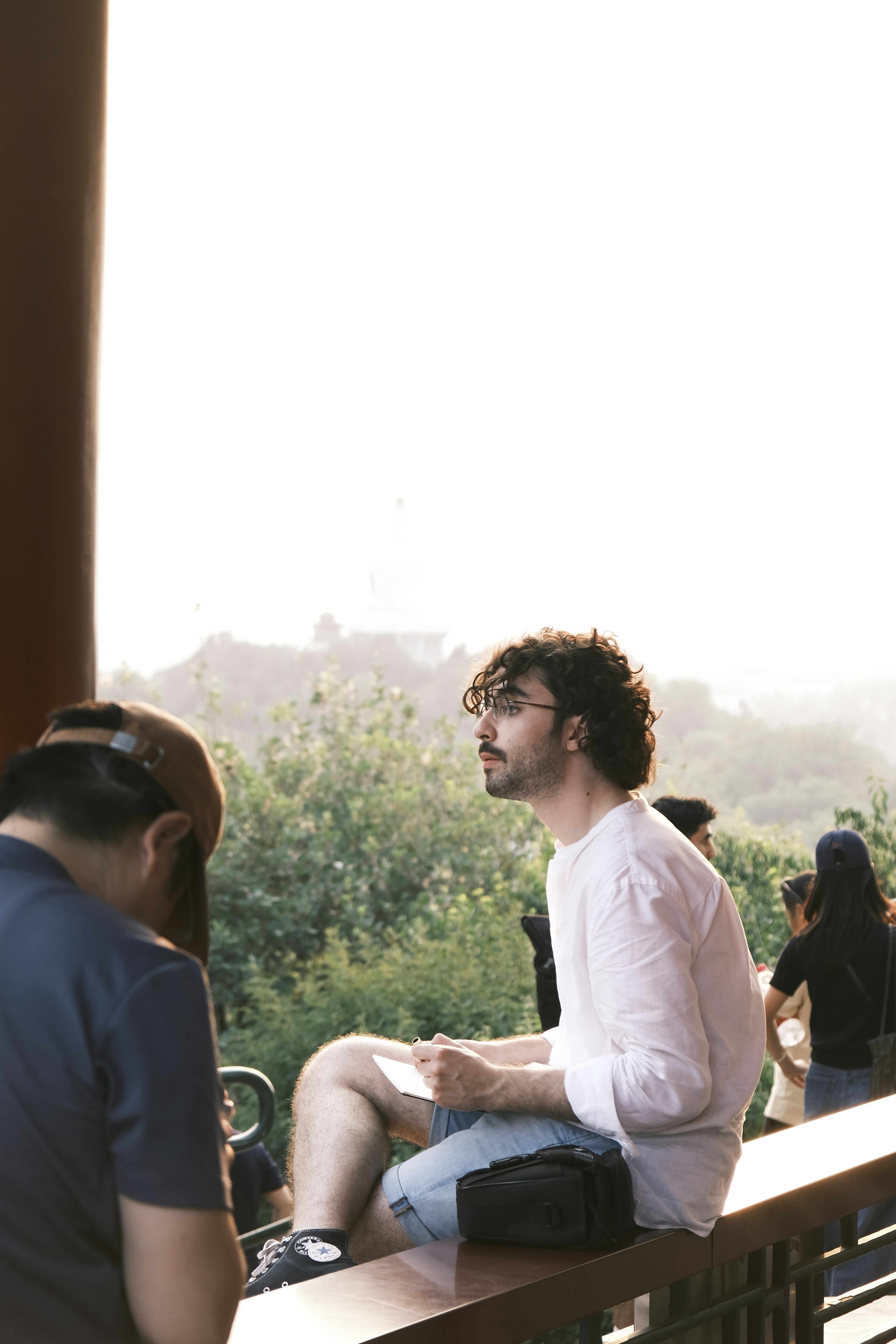 Man sitting outdoors with trees and buildings in background