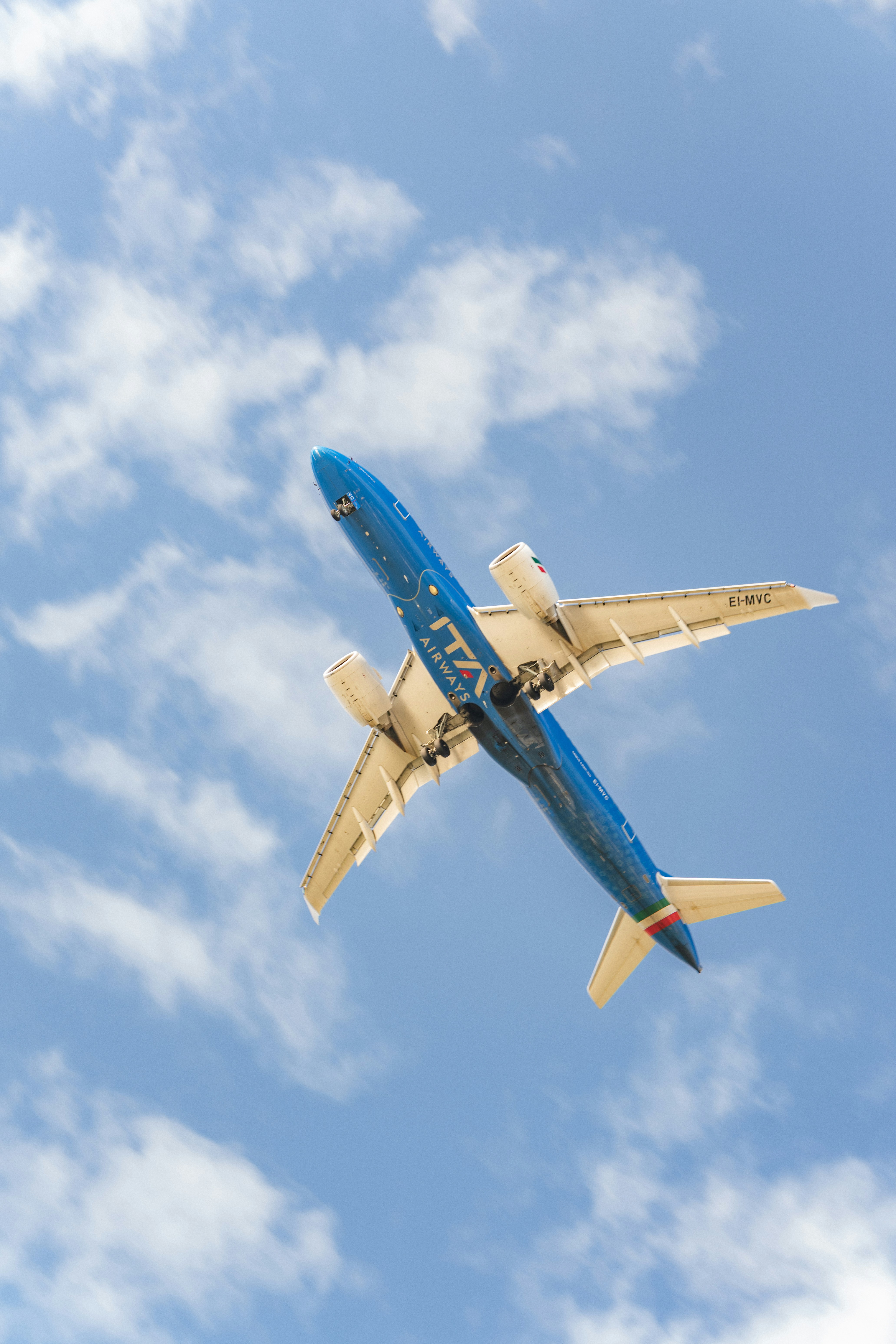 Un avion d’ita airways volant dans le ciel.