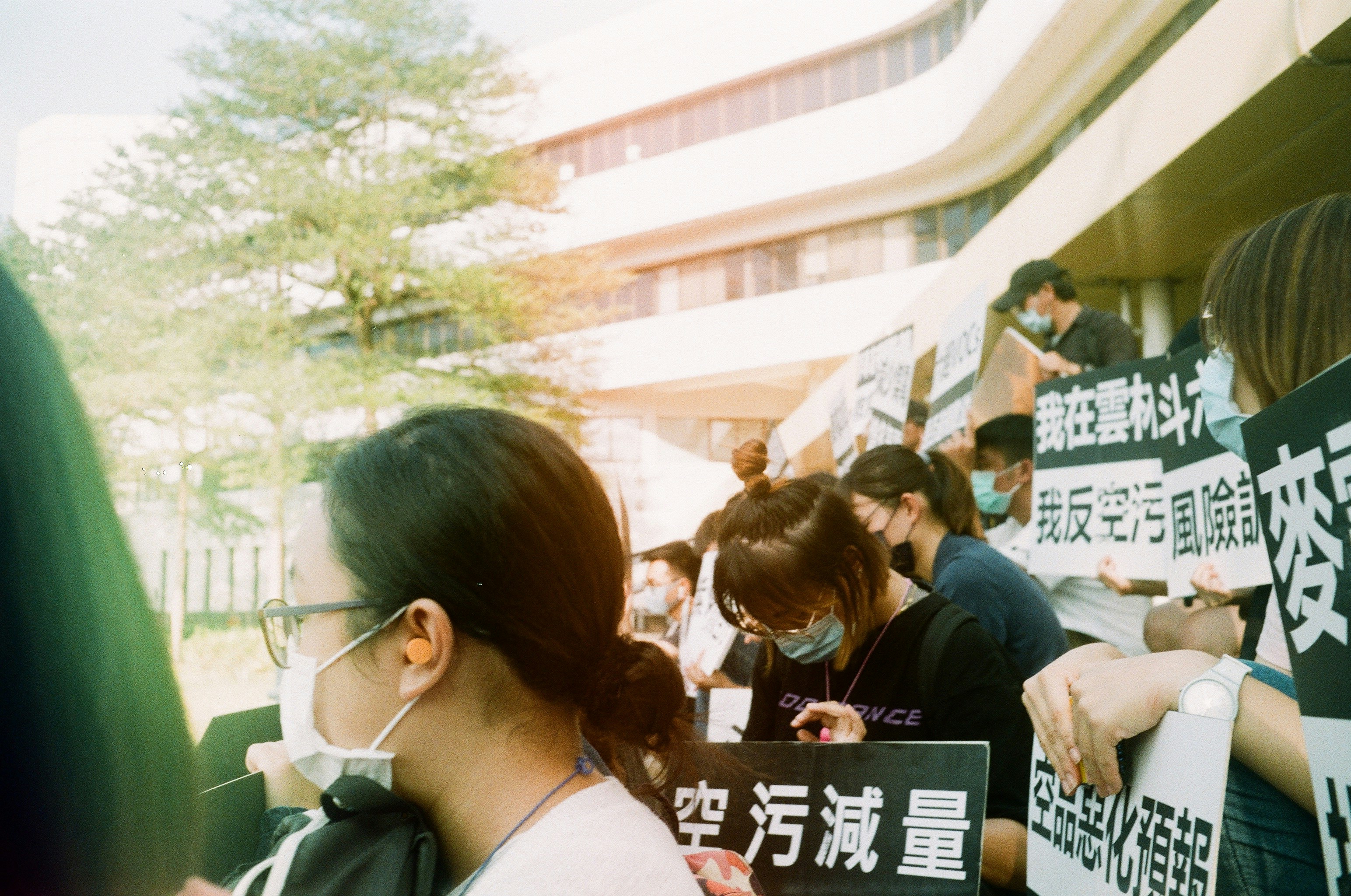 People holding signs at a protest outdoors.