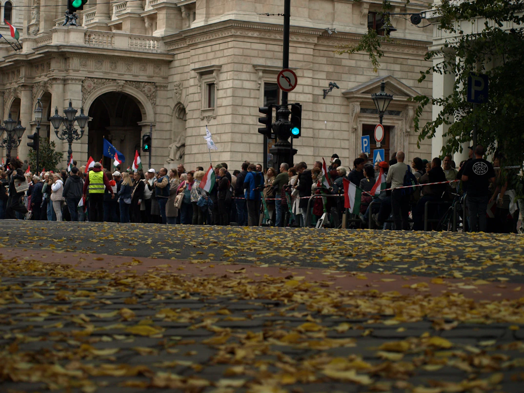 Protest rally with European and national flags, diverse crowd expressing political discontent