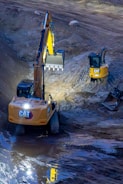 Two excavators working on a construction site at night.
