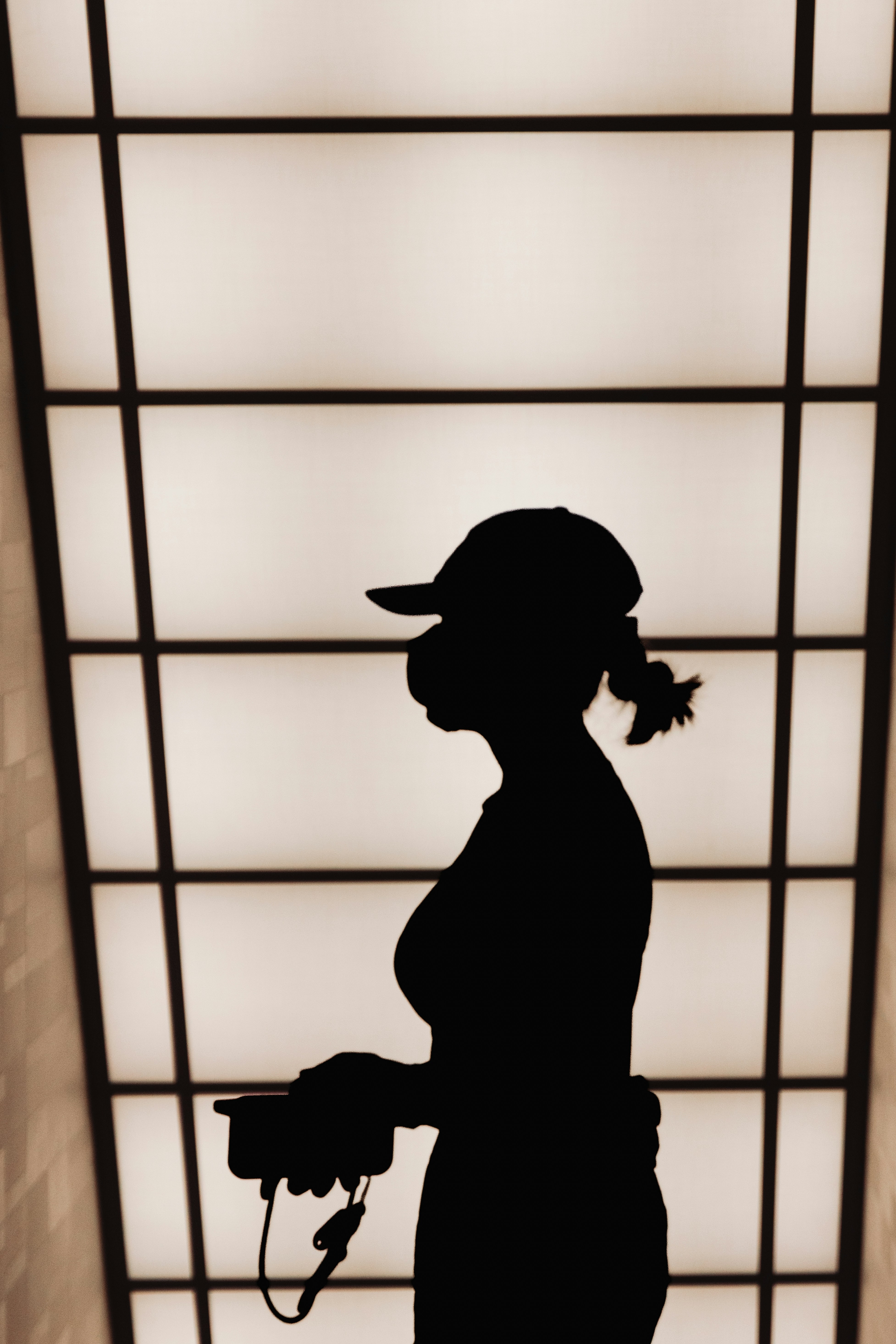 Silhouette of a person wearing a face mask and cap.