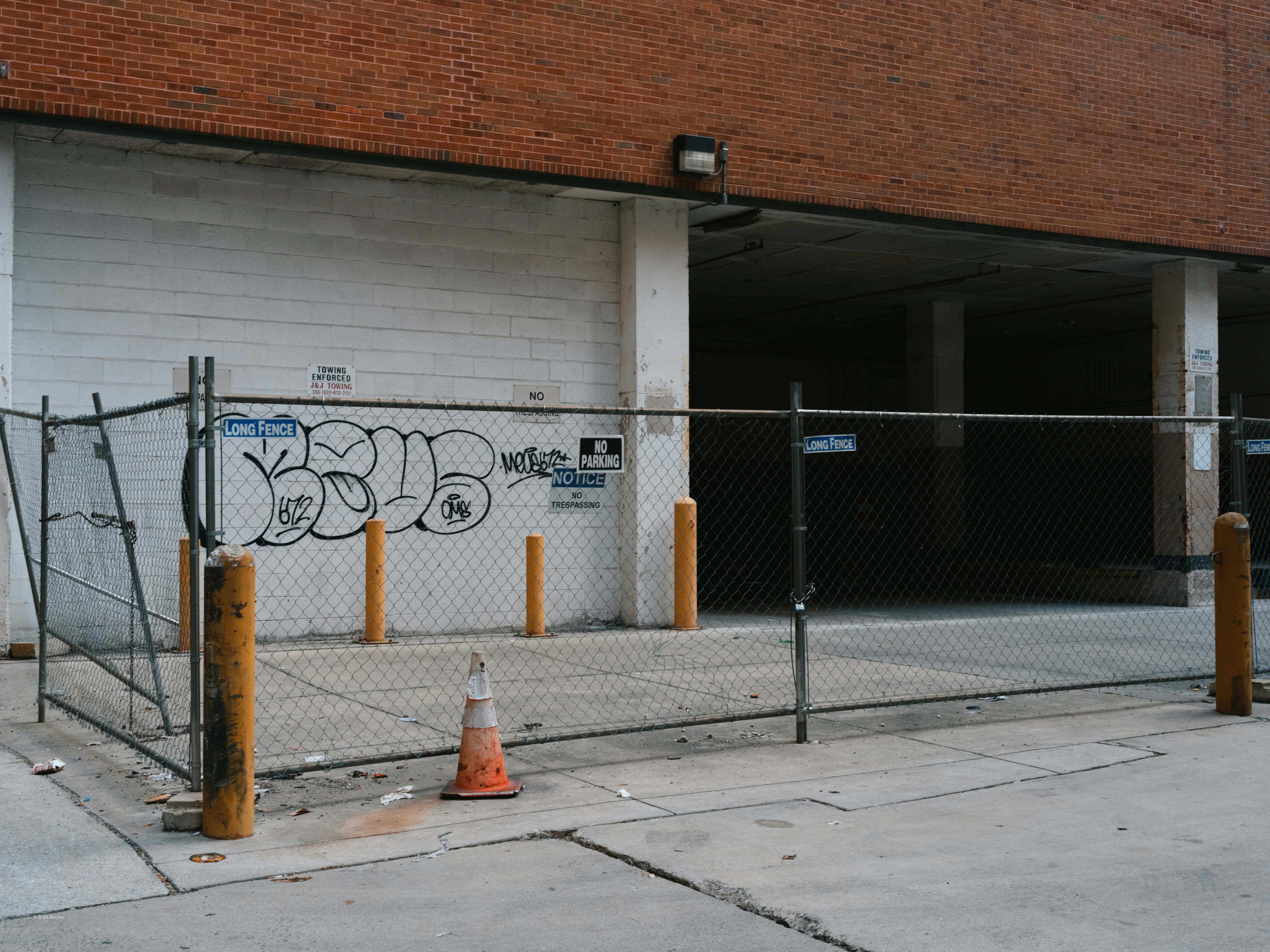 Maschendrahtzaun mit Graffiti vor dem Gebäudeeingang.