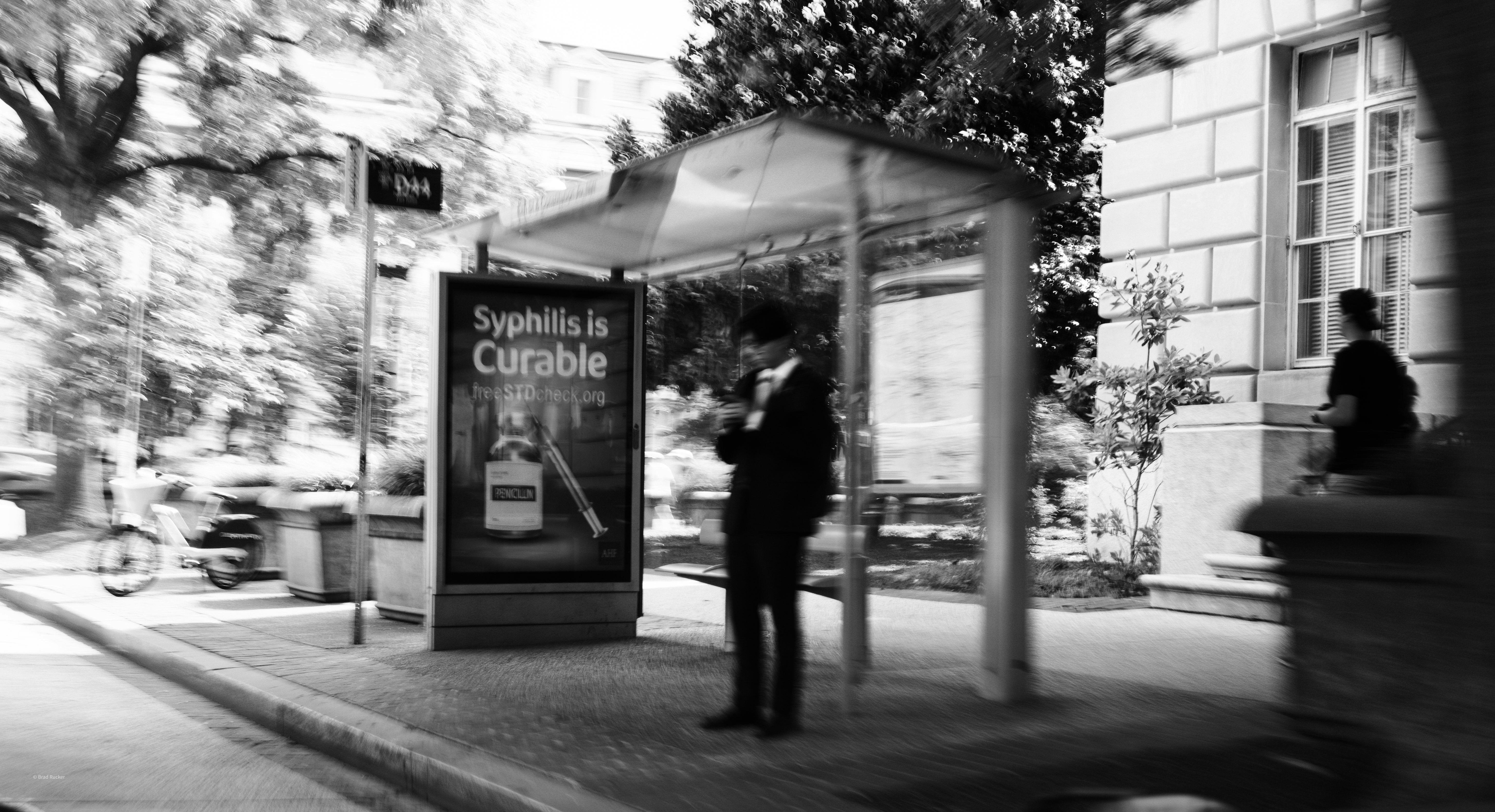 Man waiting at a bus stop with advertisement