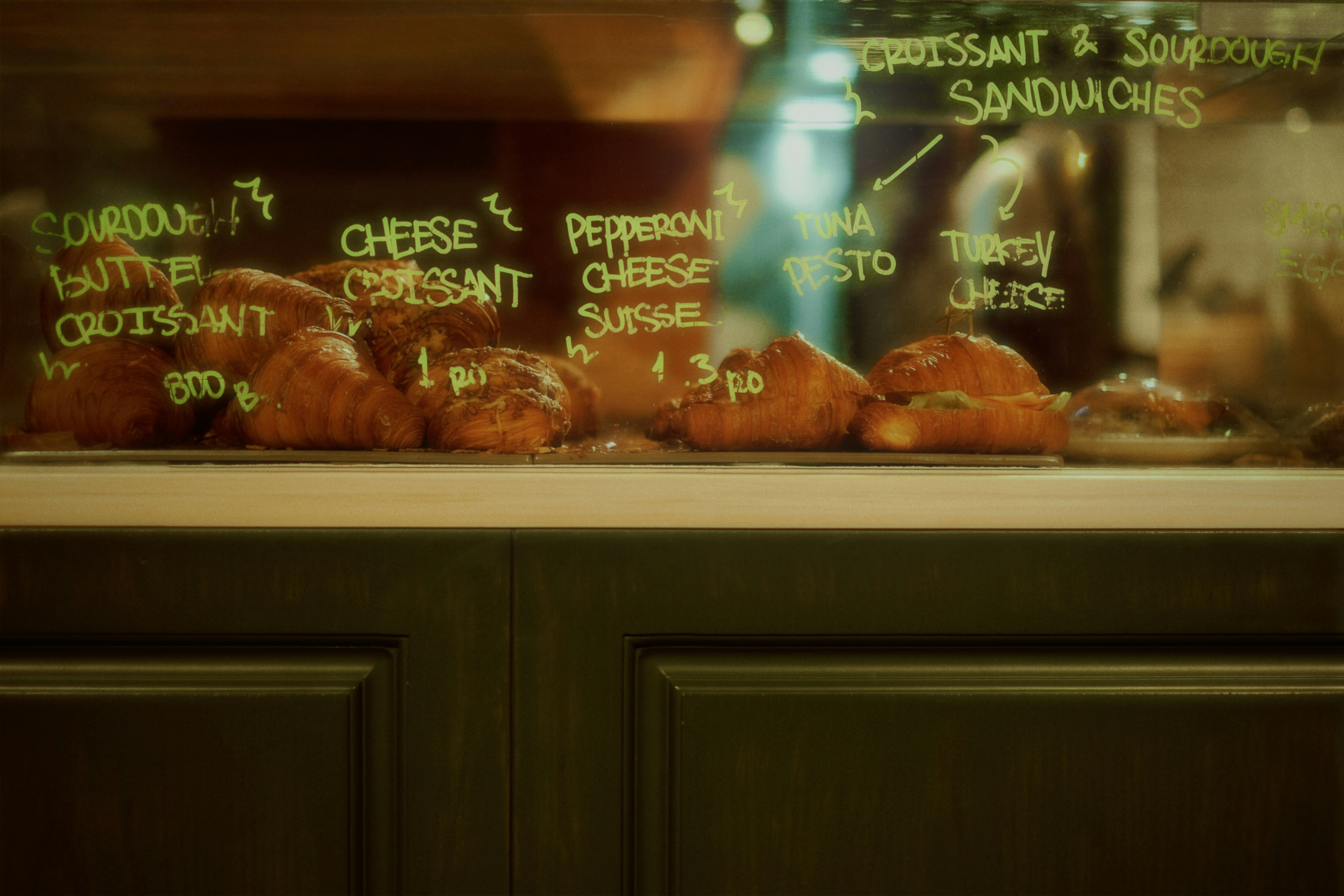 Croissants and sandwiches displayed in a cafe window.