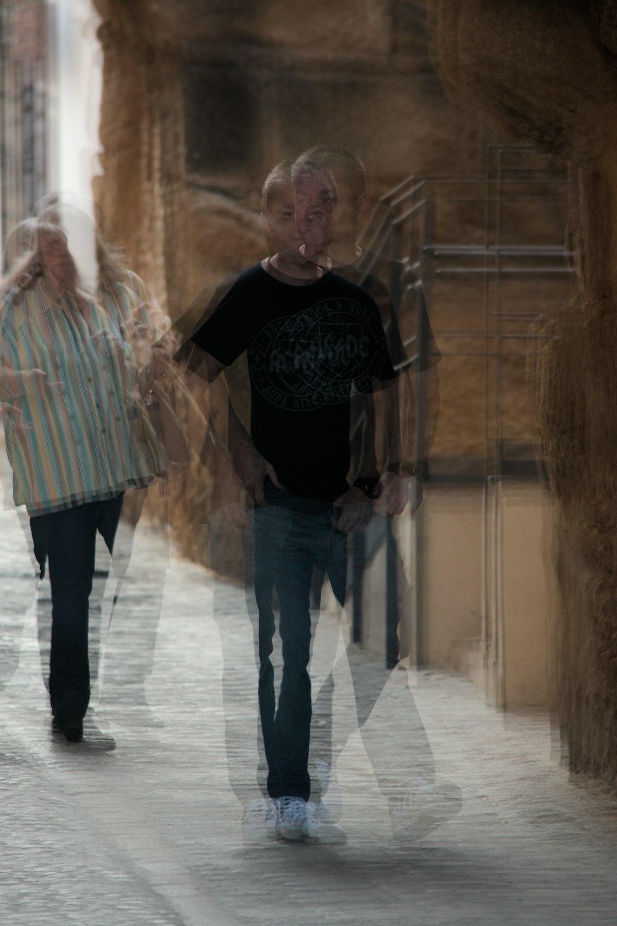 Blurred figures walking down a narrow street, intimate / painterly register